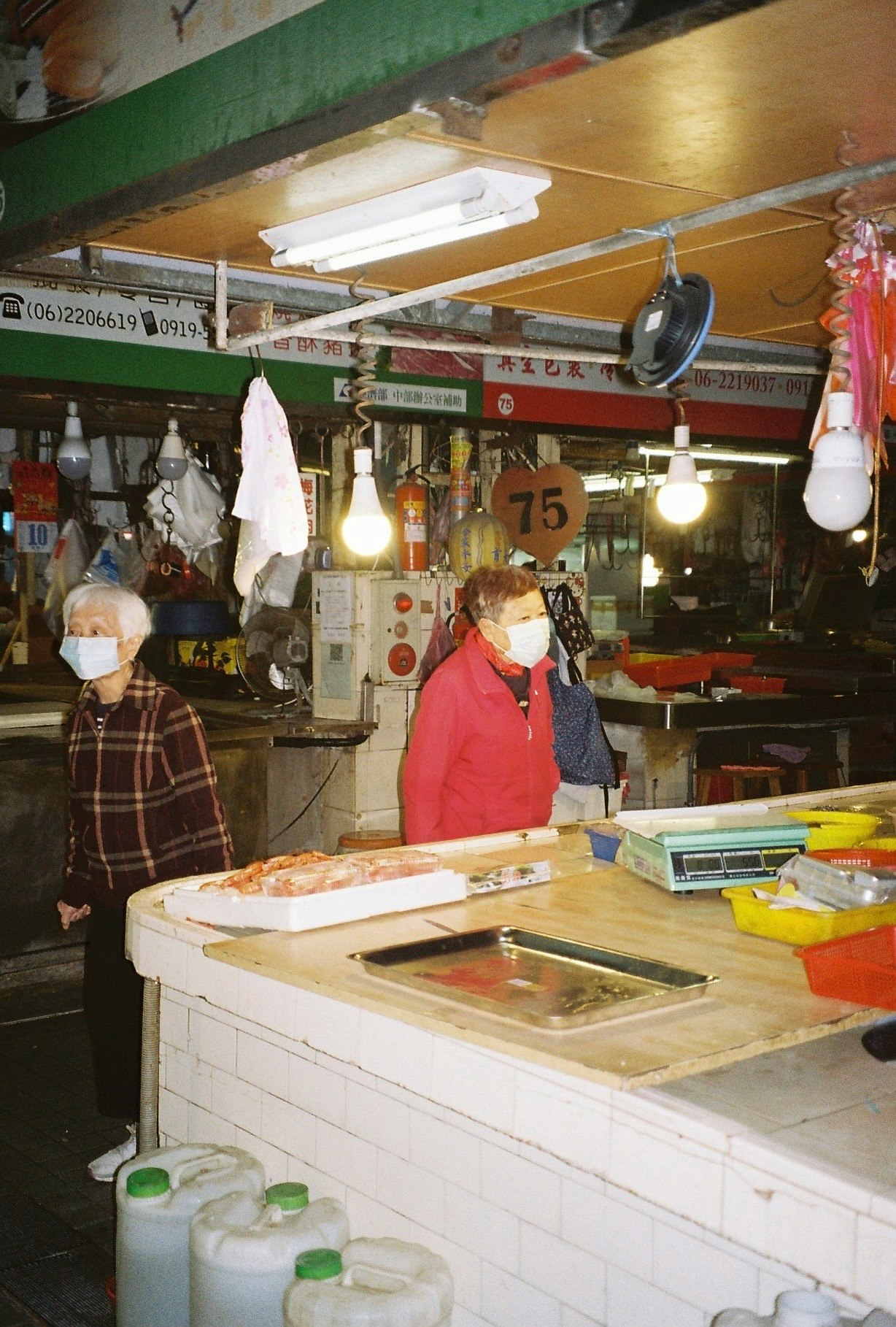 マスク姿の屋台の店先で調理台の前に立つ人々