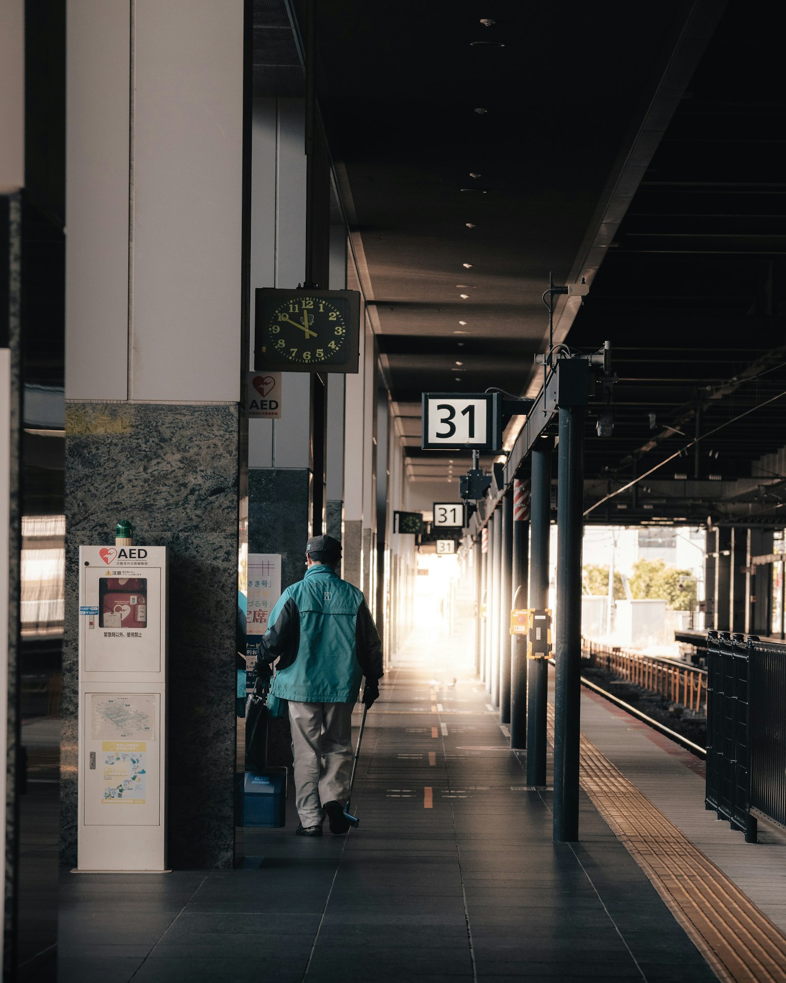 Vista de una plataforma de tren con una persona y un reloj