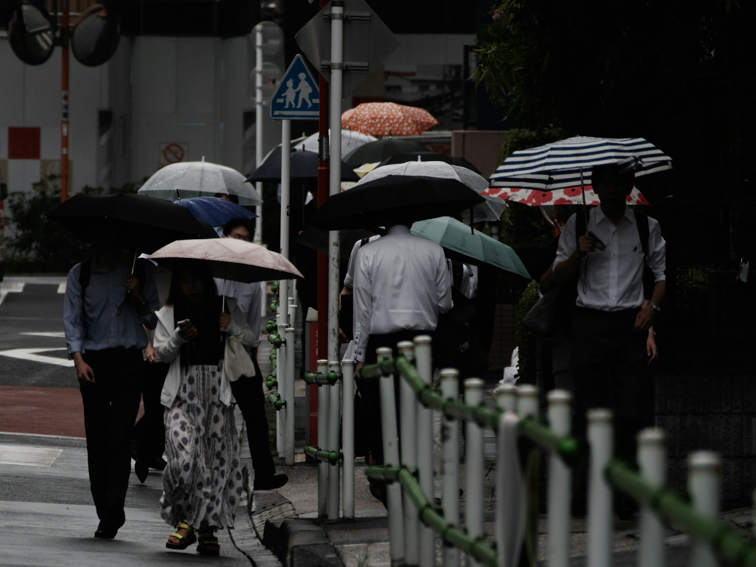 Persone che camminano per strada con ombrelli