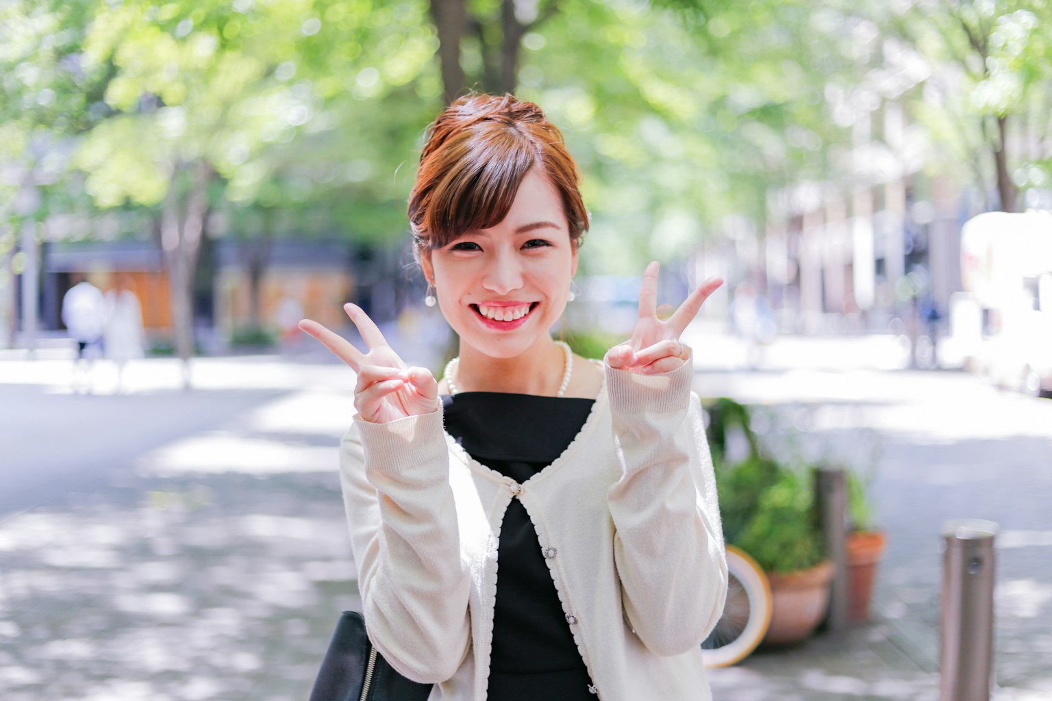 ผู้หญิงยิ้มทำสัญลักษณ์แห่งสันติภาพในสวนสว่าง