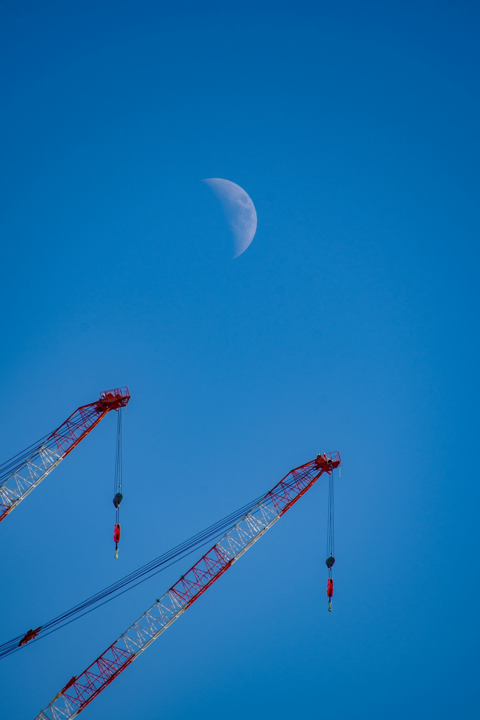 Lune croissante dans un ciel bleu avec deux grues