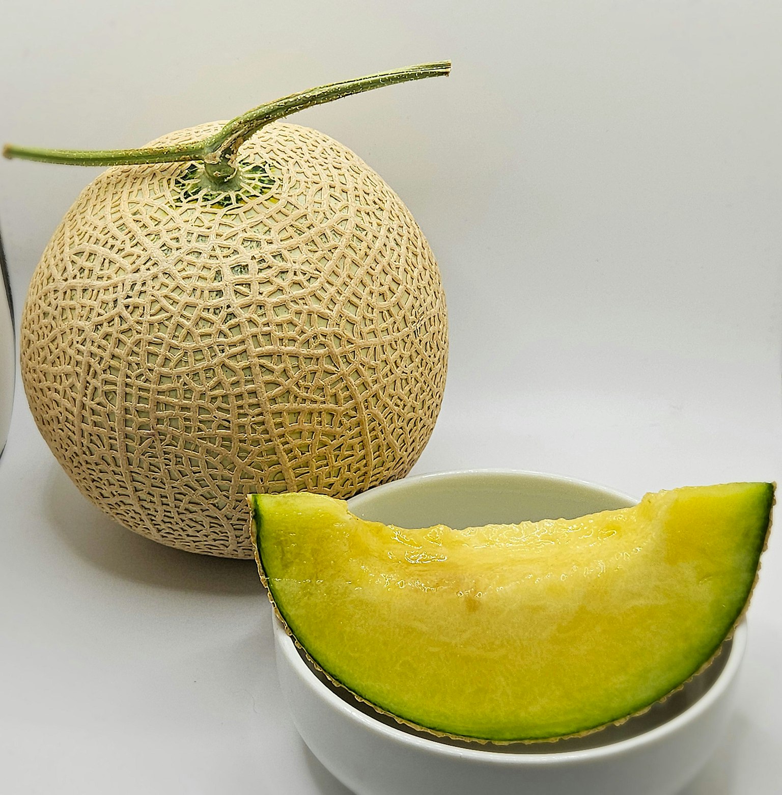 Whole cantaloupe with a slice placed on a white dish