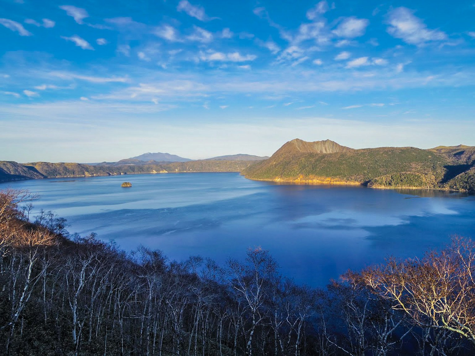 環繞著山脈的湖泊美景，藍天白雲