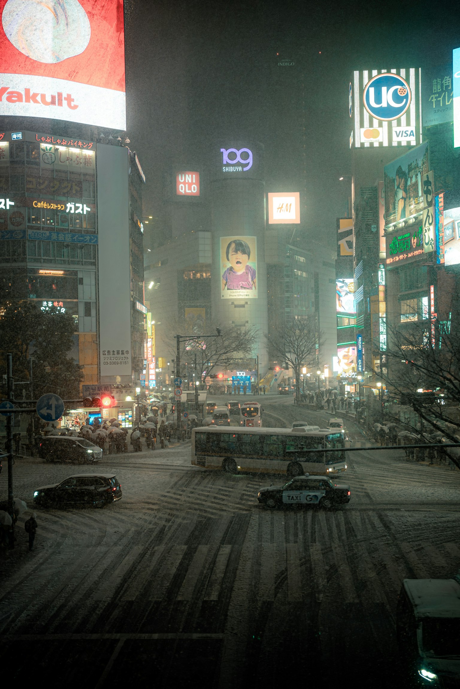 Snowy night scene of Shibuya Crossing with visible billboards and cars