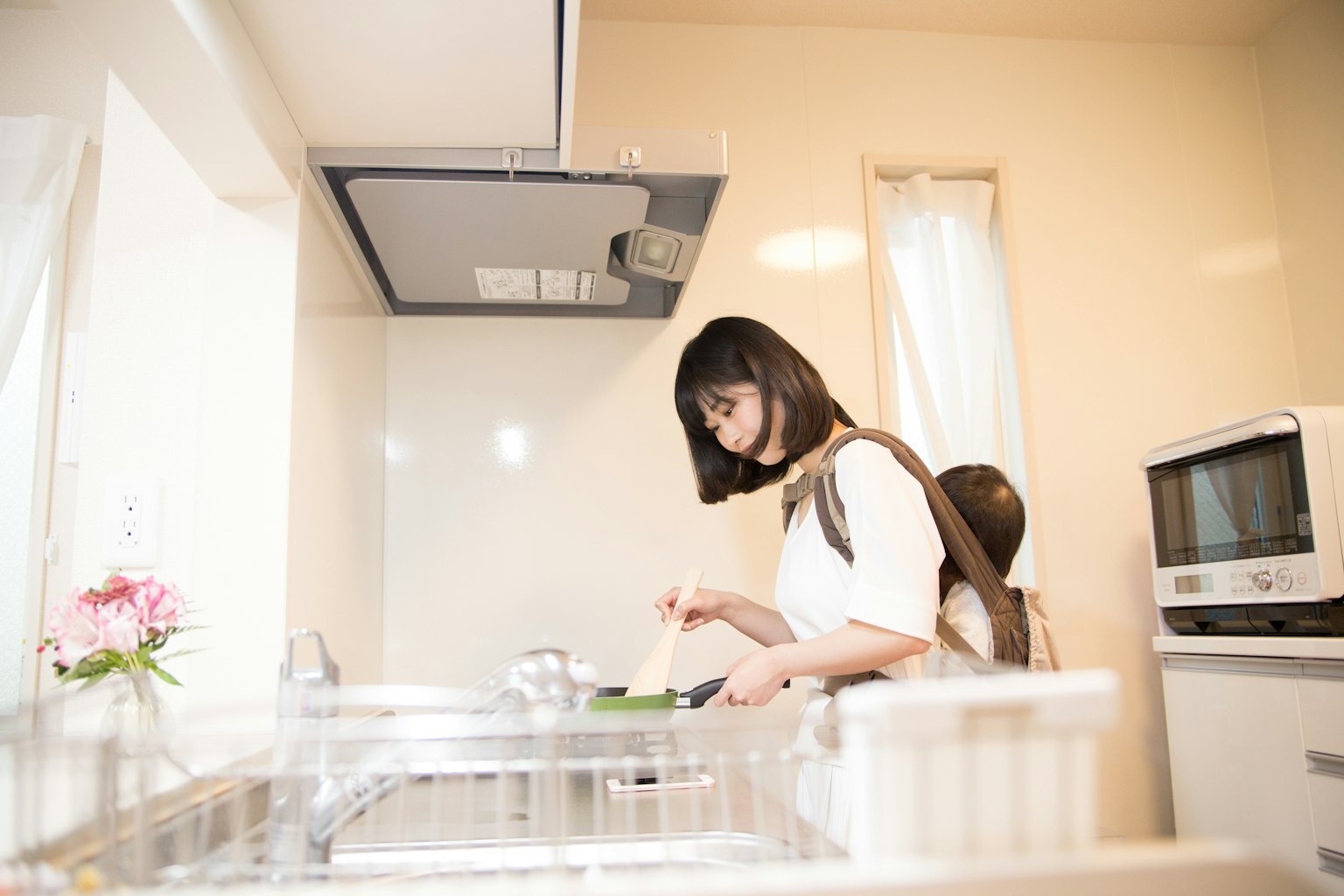Une femme cuisinant dans une cuisine lumineuse avec un petit enfant