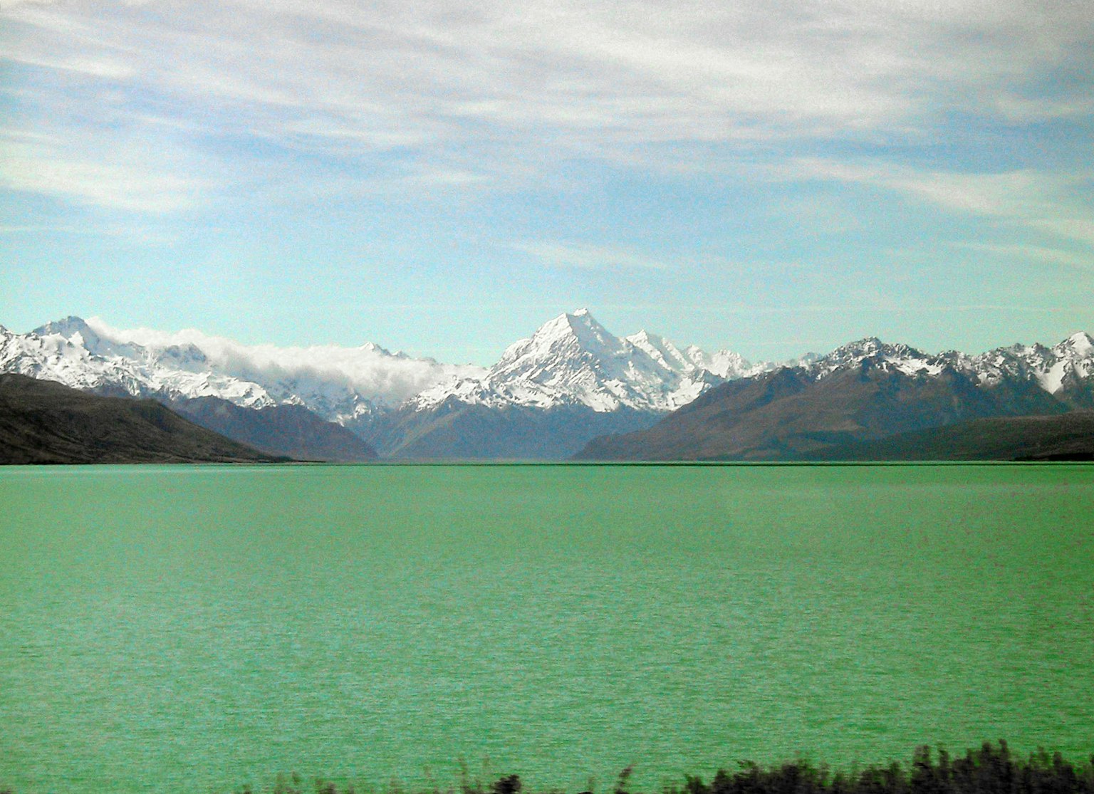 Vista escénica de un lago turquesa con montañas nevadas al fondo