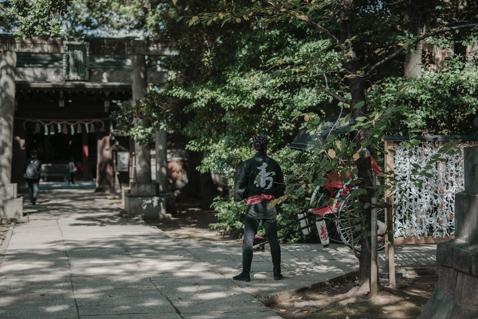 A person standing in front of a shrine with a lush green background