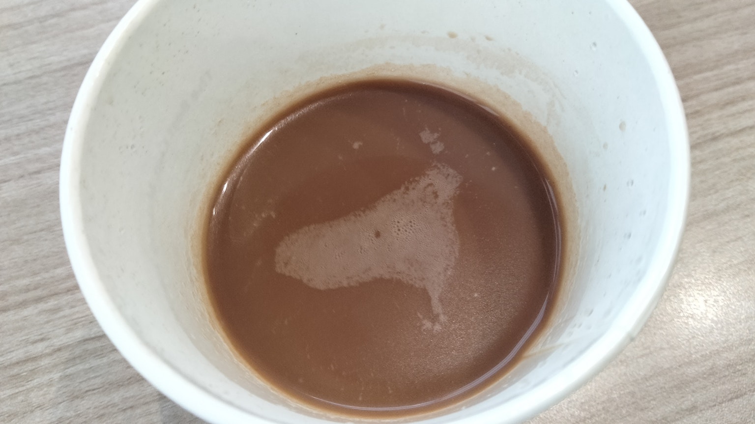 上方視角的白色杯子內有棕色液體