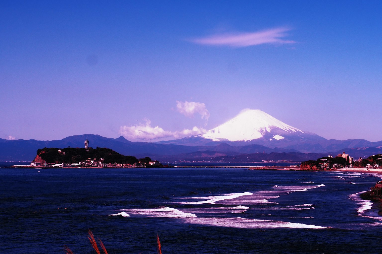 Vista costera con el monte Fuji un cielo azul y olas