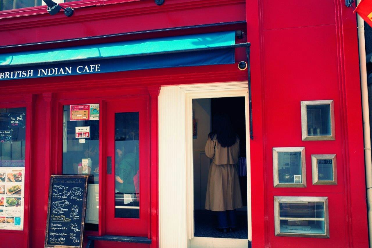 Eingang eines Cafés mit roter Fassade und Menüschilden
