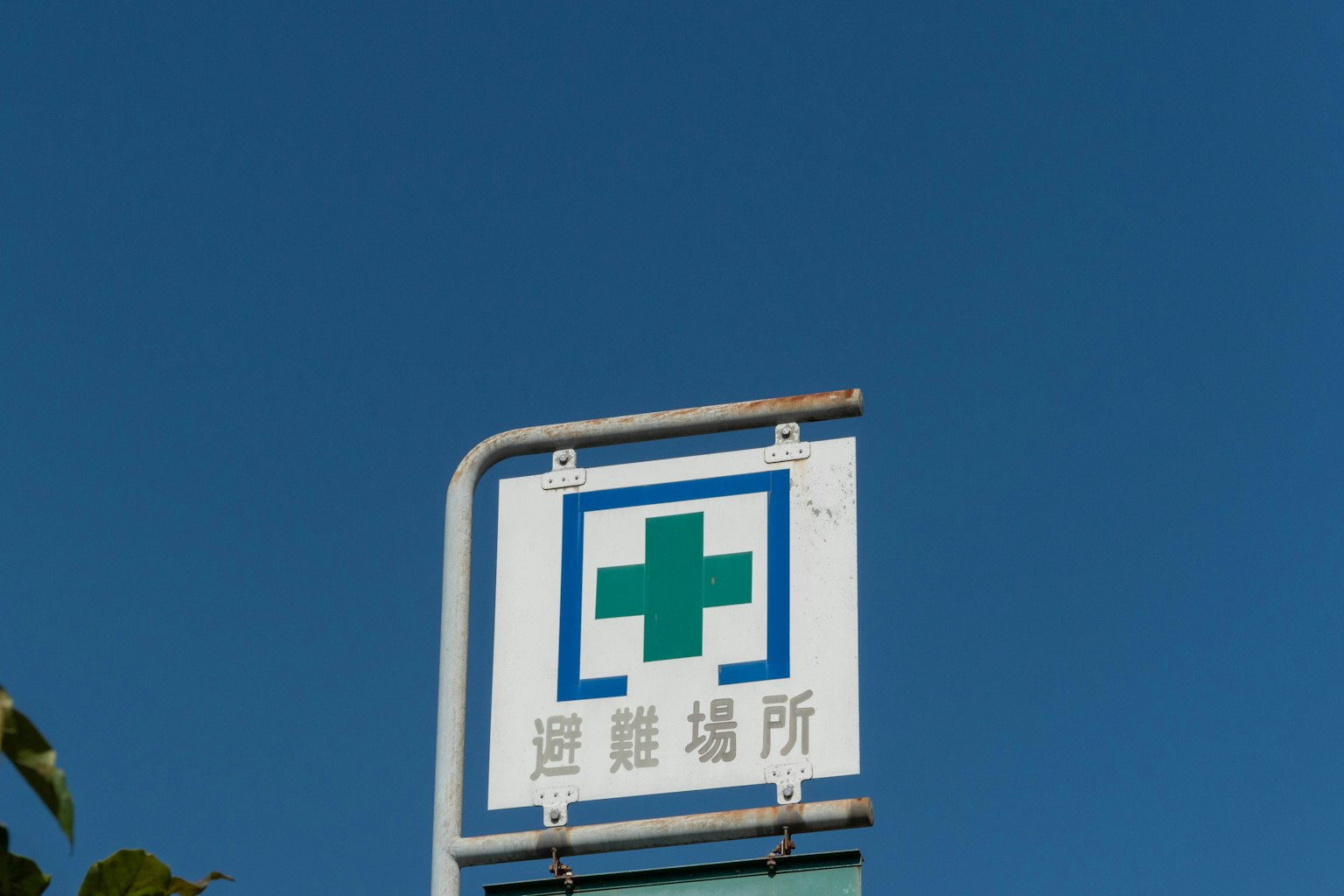 Cartel de farmacia con una cruz verde contra un cielo azul