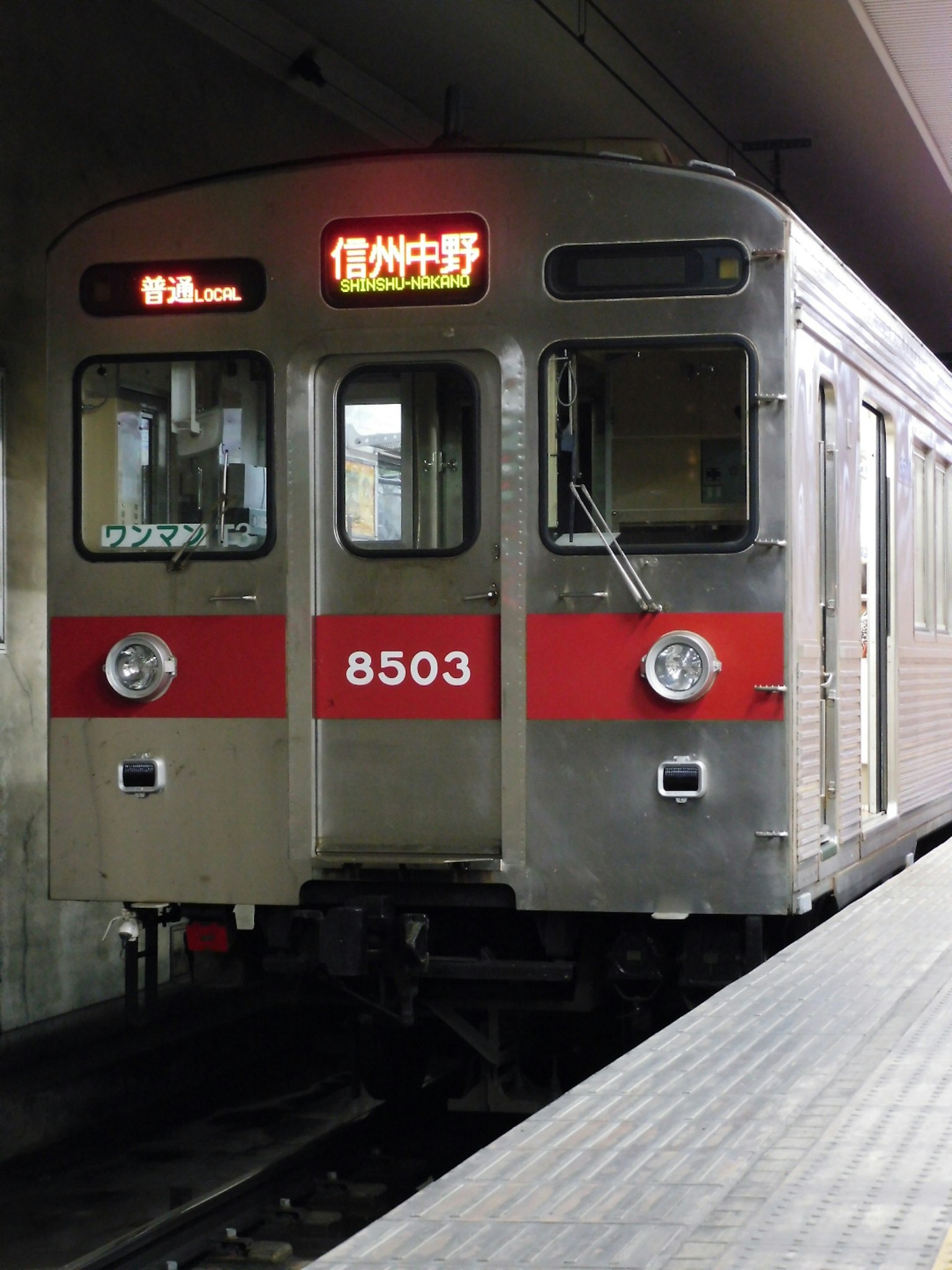 Train argenté avec des rayures rouges arrêté à une station