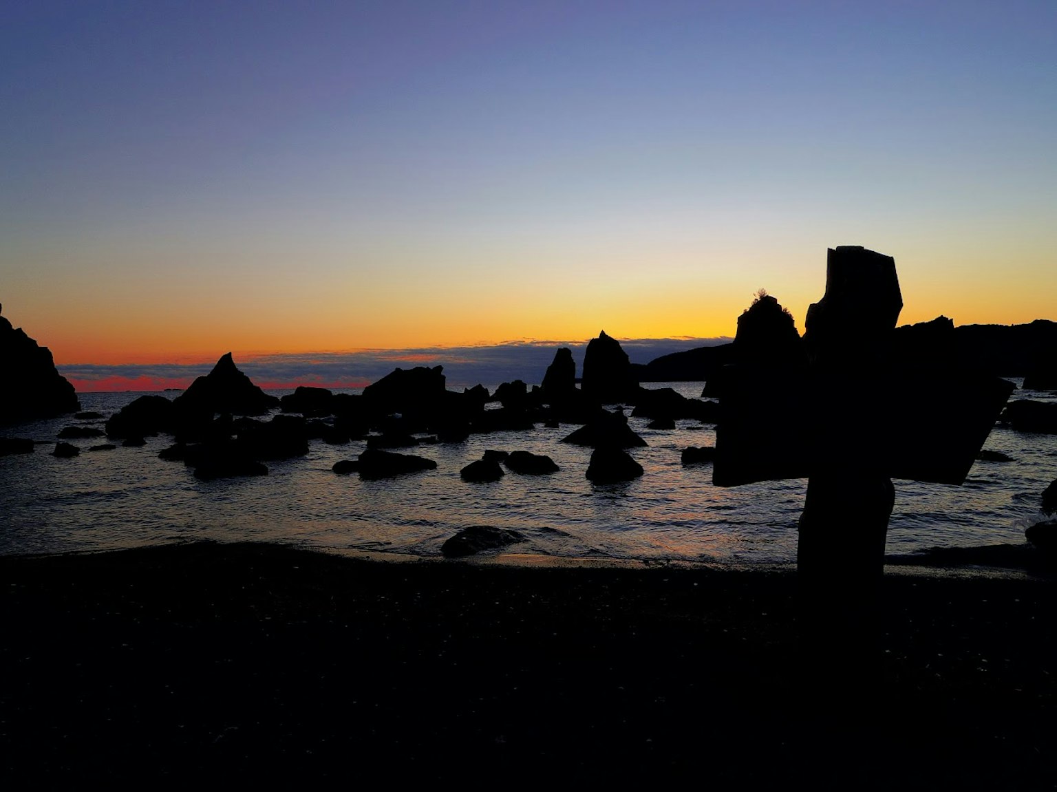 Silhouette di rocce contro una spiaggia al tramonto