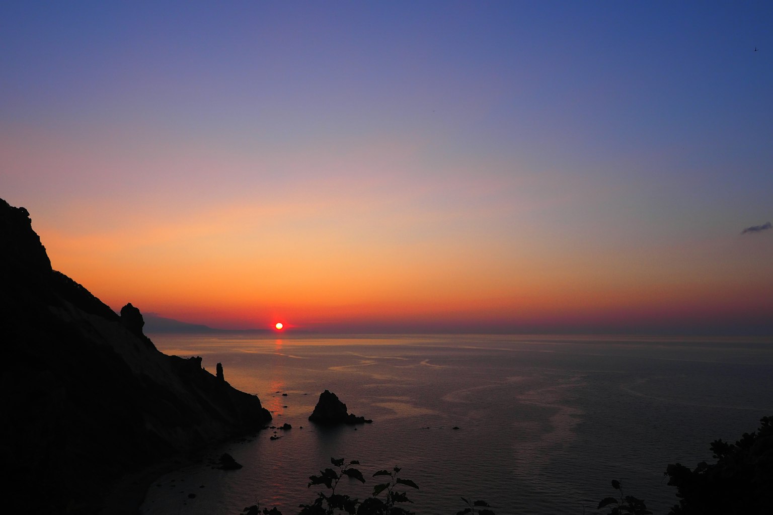 Schöner Sonnenuntergang über dem Ozean mit Silhouetten von Felsen