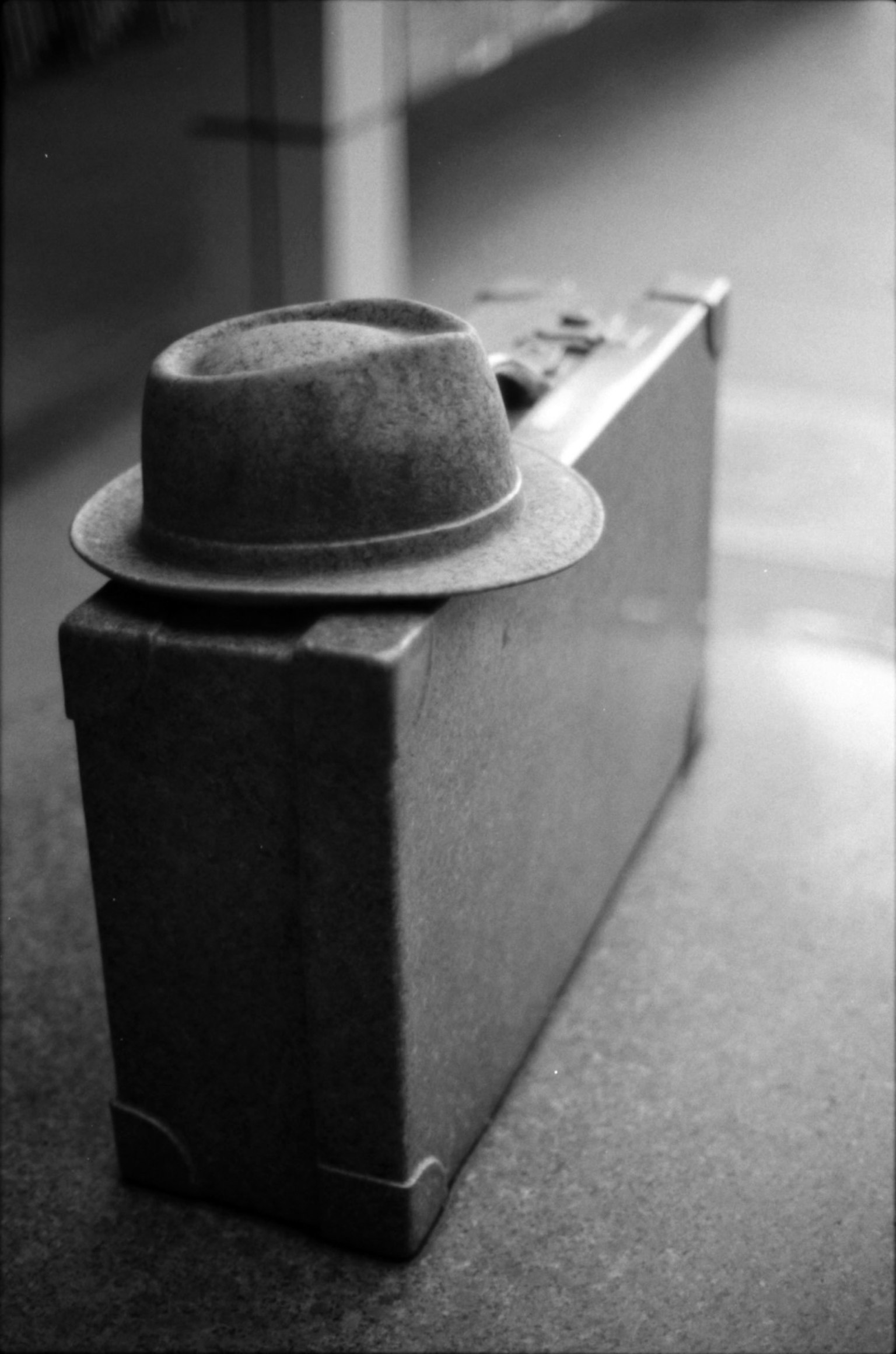 A fedora hat placed on top of a black and white suitcase