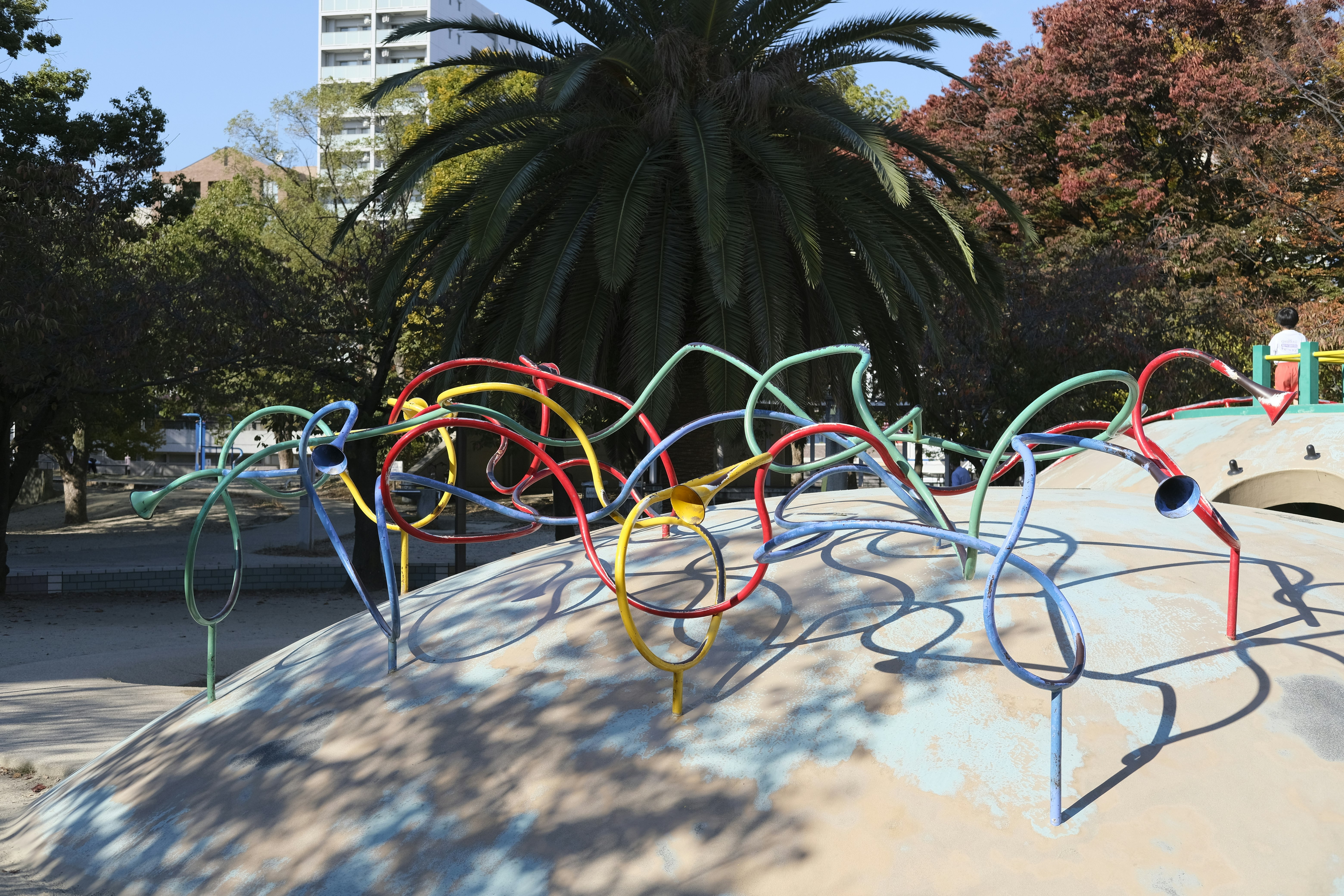 公園の遊具に並ぶカラフルなバネ式乗り物の列