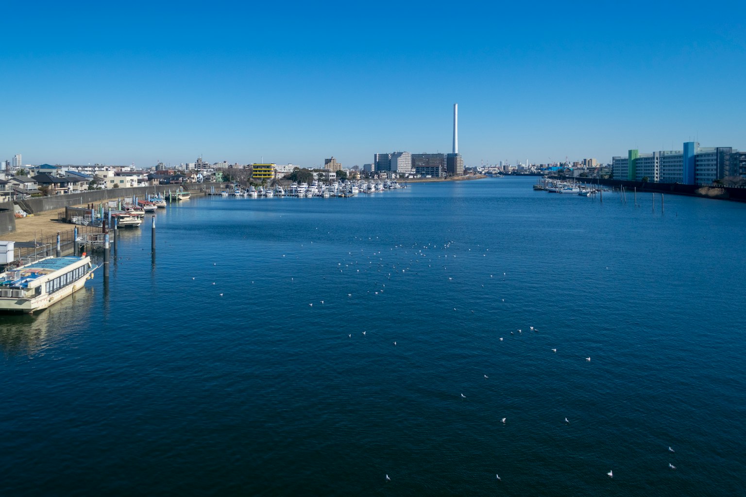 Paesaggio fluviale con cielo blu chiaro e acqua calma con barche e edifici della città