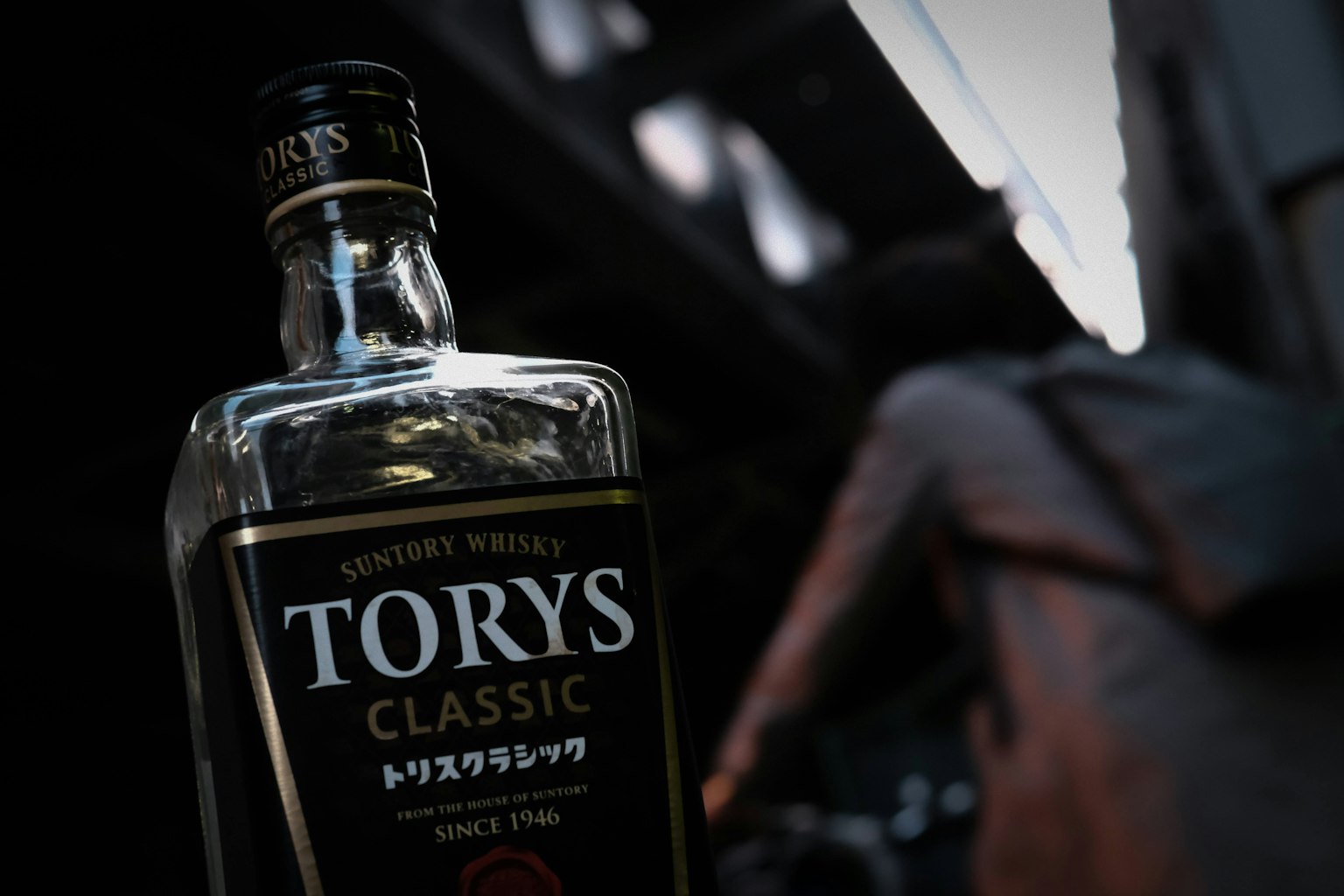 Une bouteille de whiskey Torys placée sur un fond sombre réfléchissant la lumière