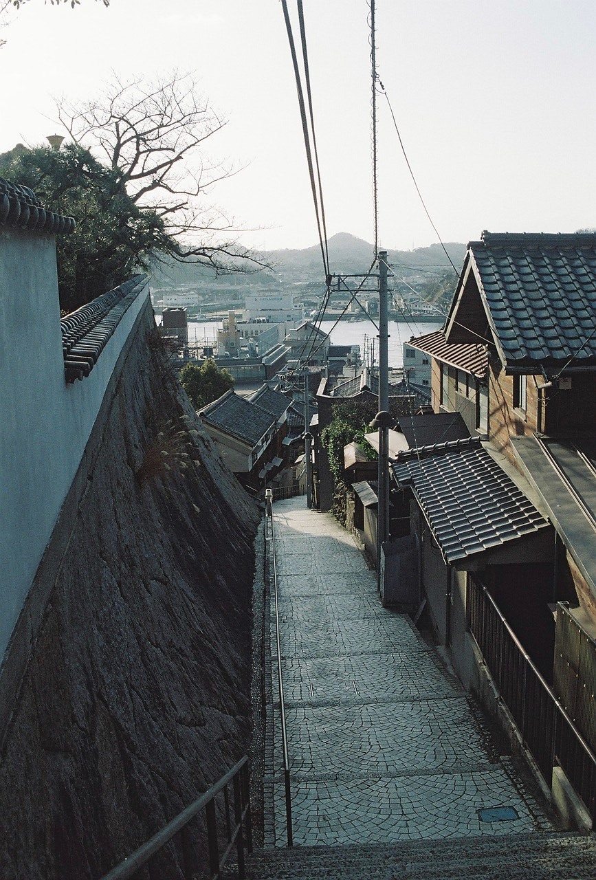 坂道の路地と家並み、遠くに山並みが見える景色