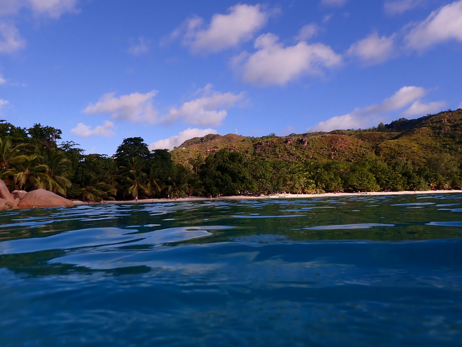 Pemandangan laut biru dengan bukit hijau di latar belakang