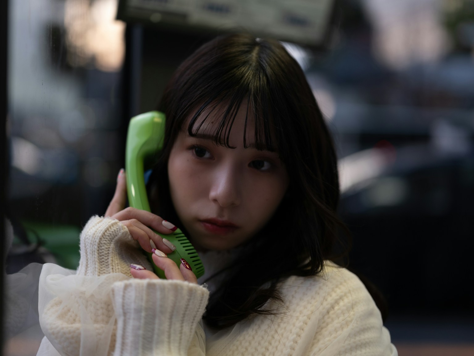 Portrait of a woman holding a green phone receiver against a dark background