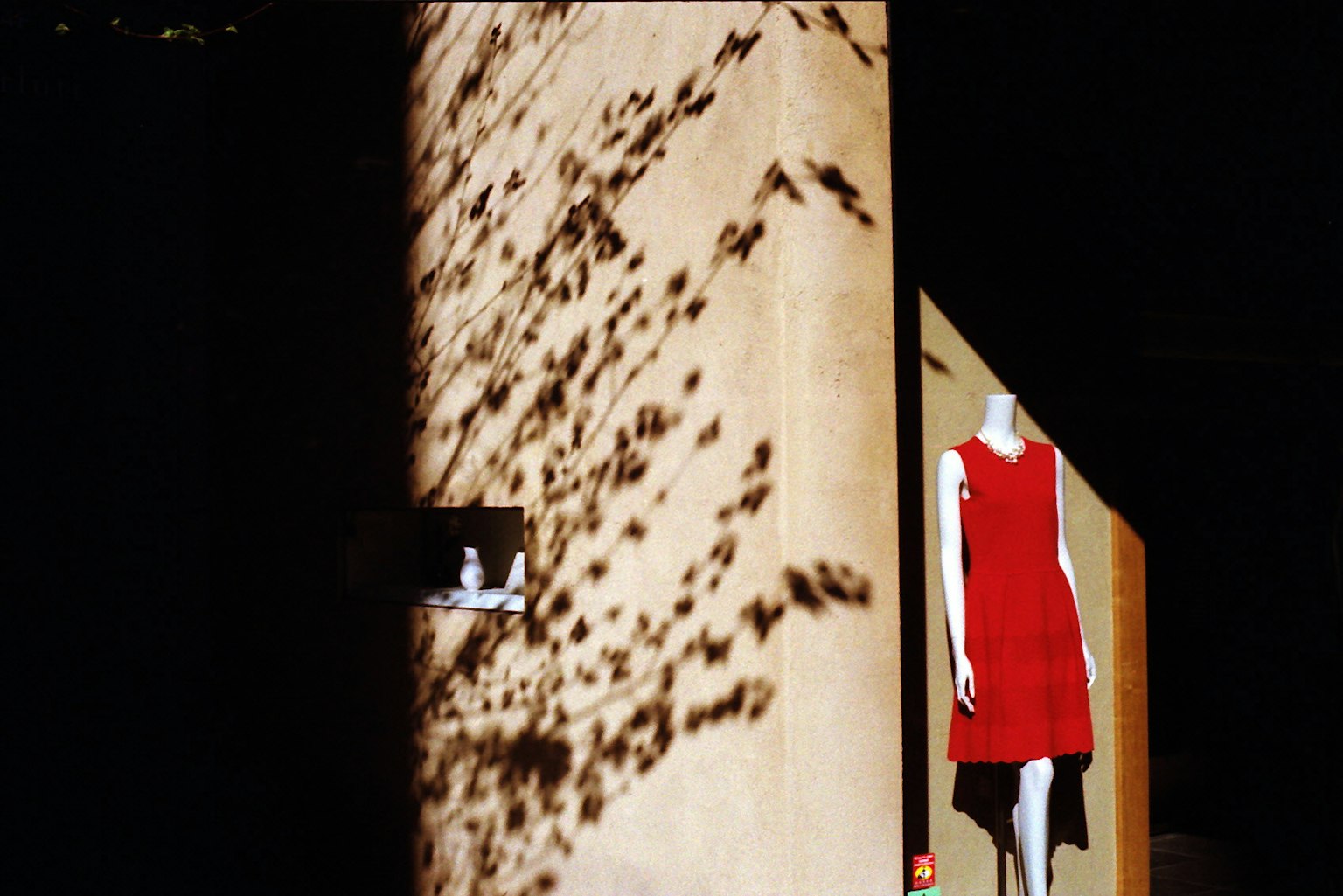 Spazio espositivo con un abito rosso e ombre sul muro