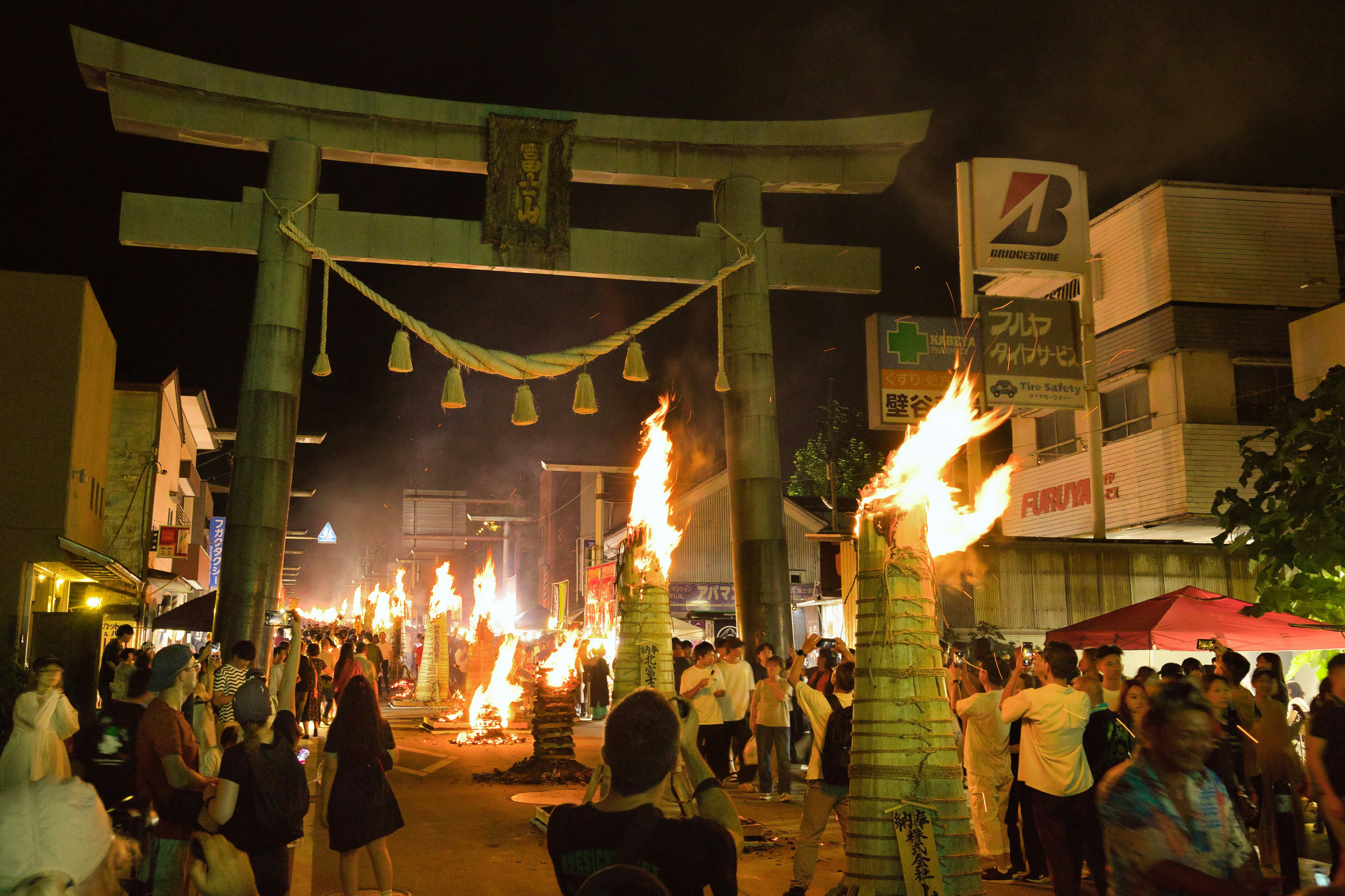 富士吉田の火祭りで燃え上がる松明と人々の夜の通り