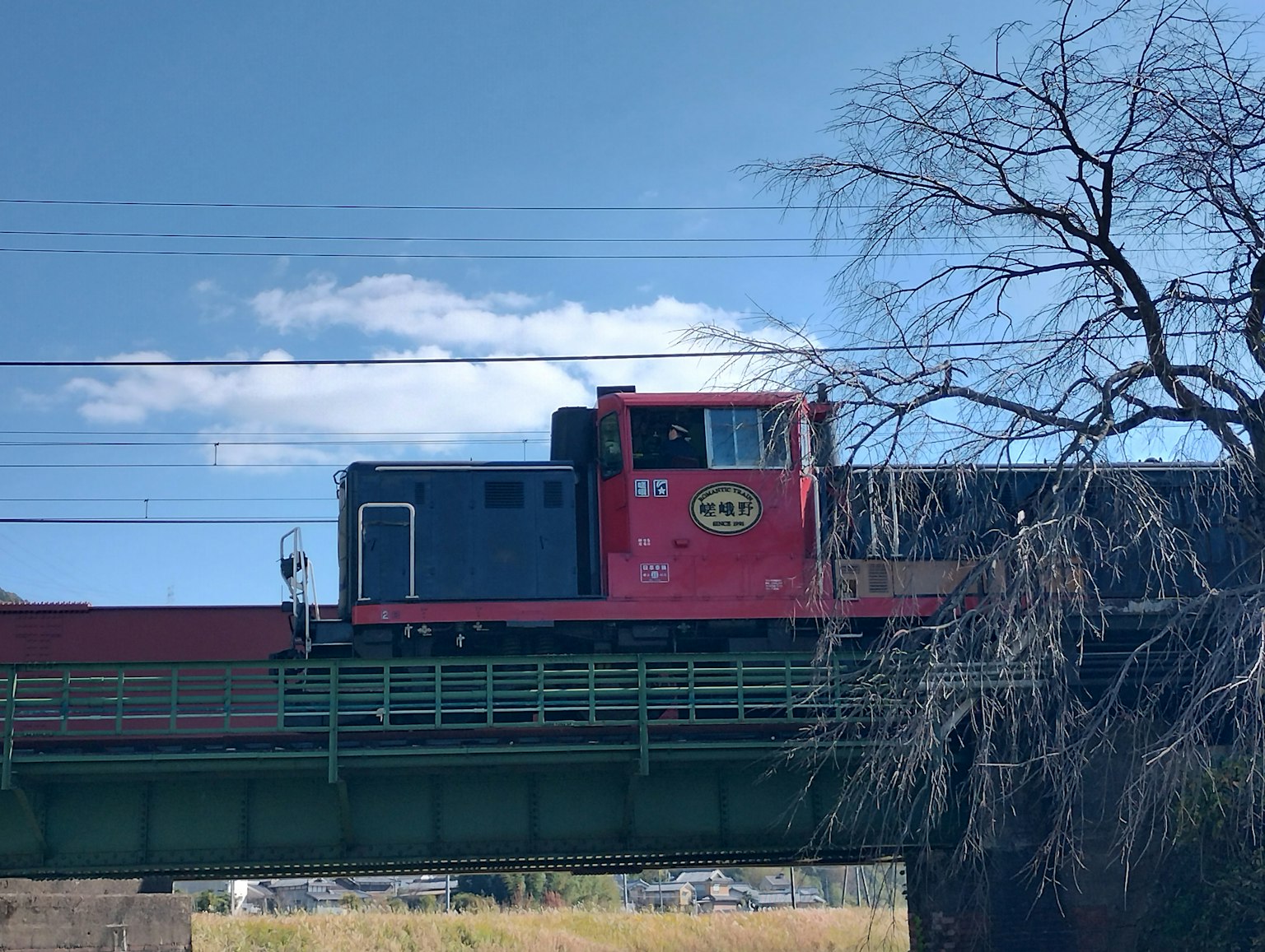 Red locomotive running on a bridge under a blue sky