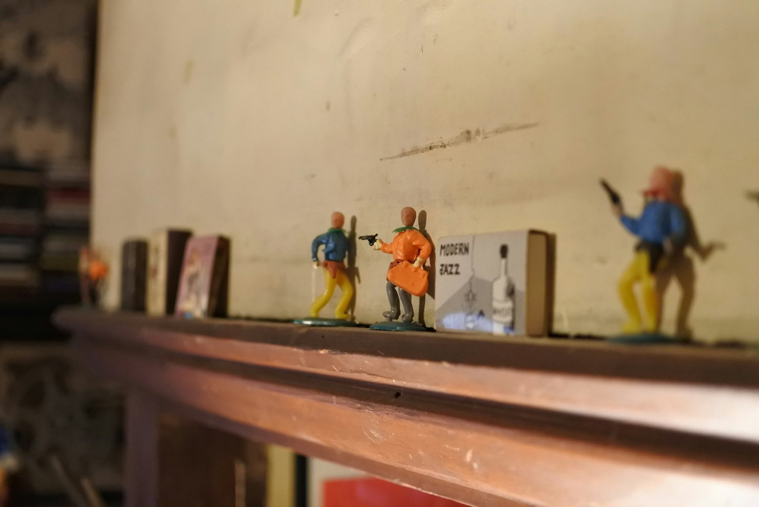 Figure in plastica colorate allineate su uno scaffale con un muro testurizzato sullo sfondo