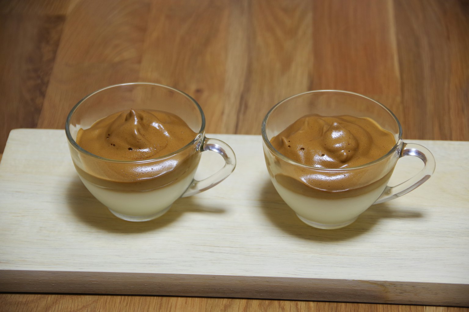 两个玻璃杯，装有奶油甜点，上面加有打发的咖啡奶油