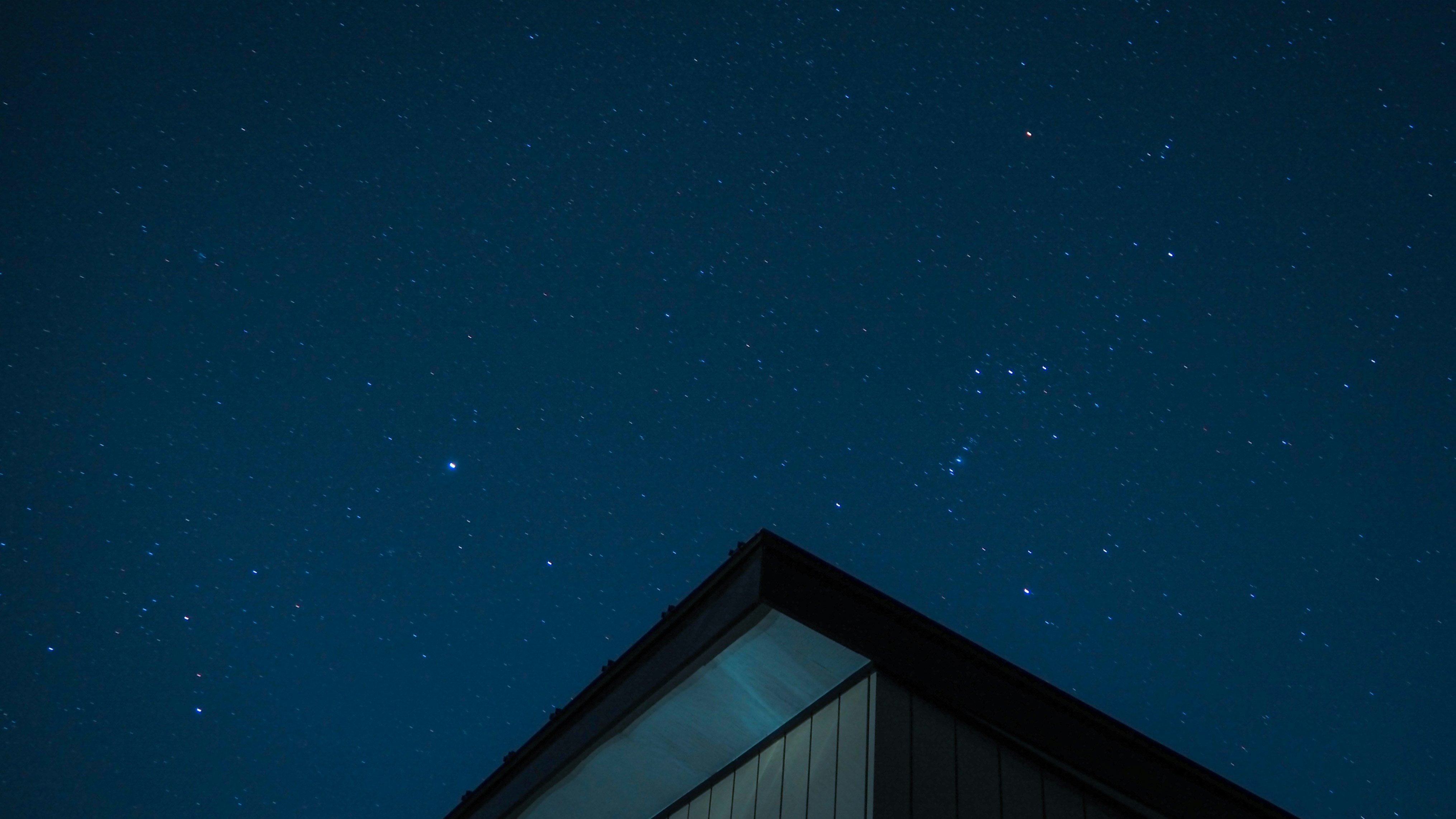 starry night sky with a building roof silhouette