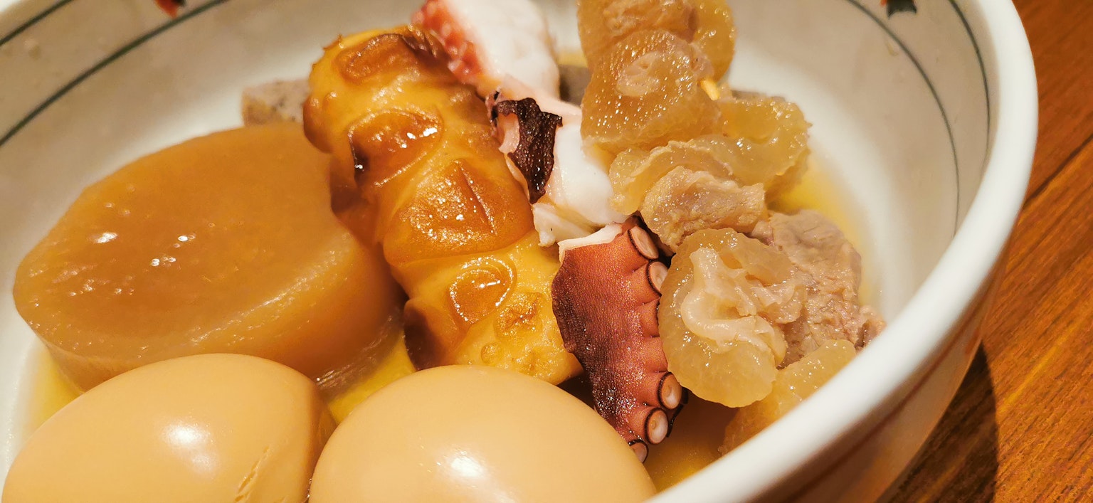 Tazón de plato guisado caliente con huevos y patas de pulpo