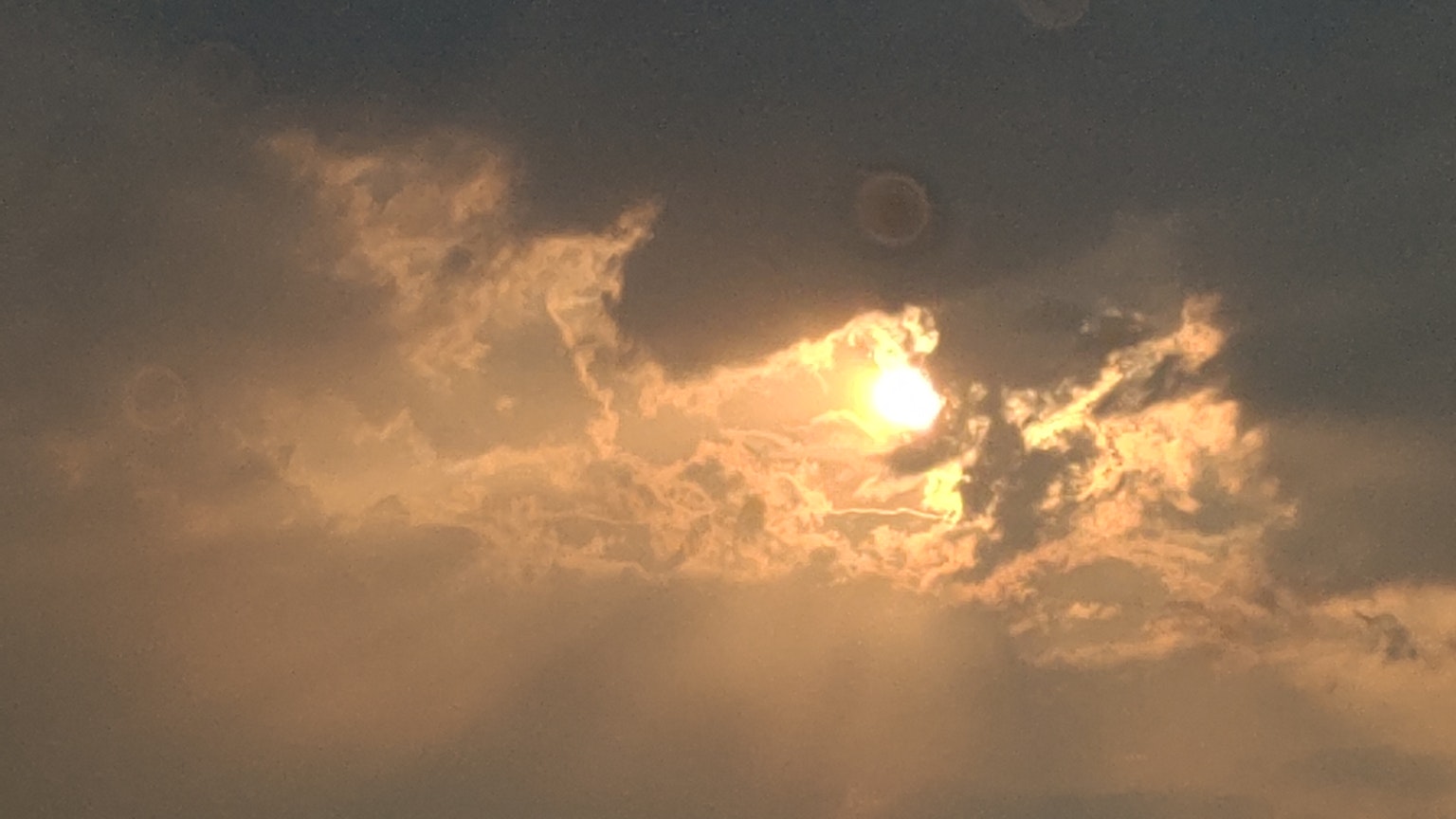 Luce del sole che filtra tra nuvole scure con un cielo drammatico