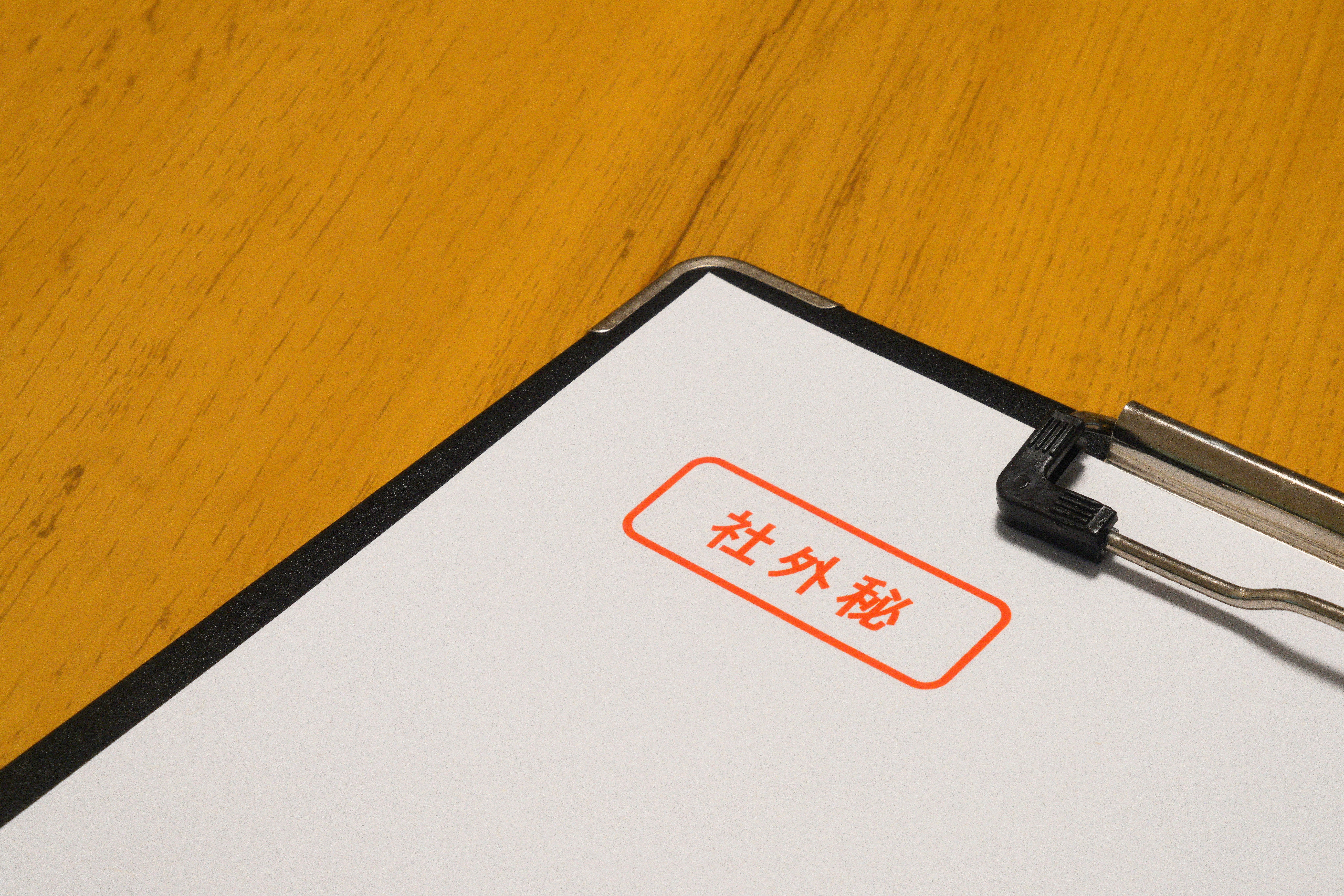 オレンジの文字が入った書類とクリップボード