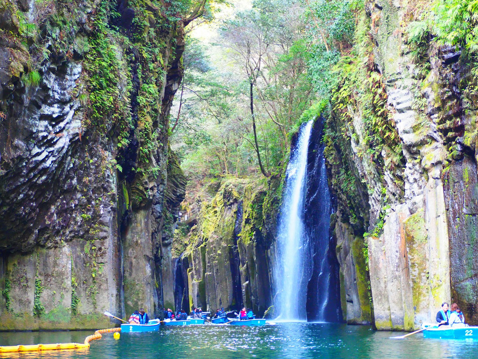 A serene water area surrounded by lush cliffs and a beautiful waterfall