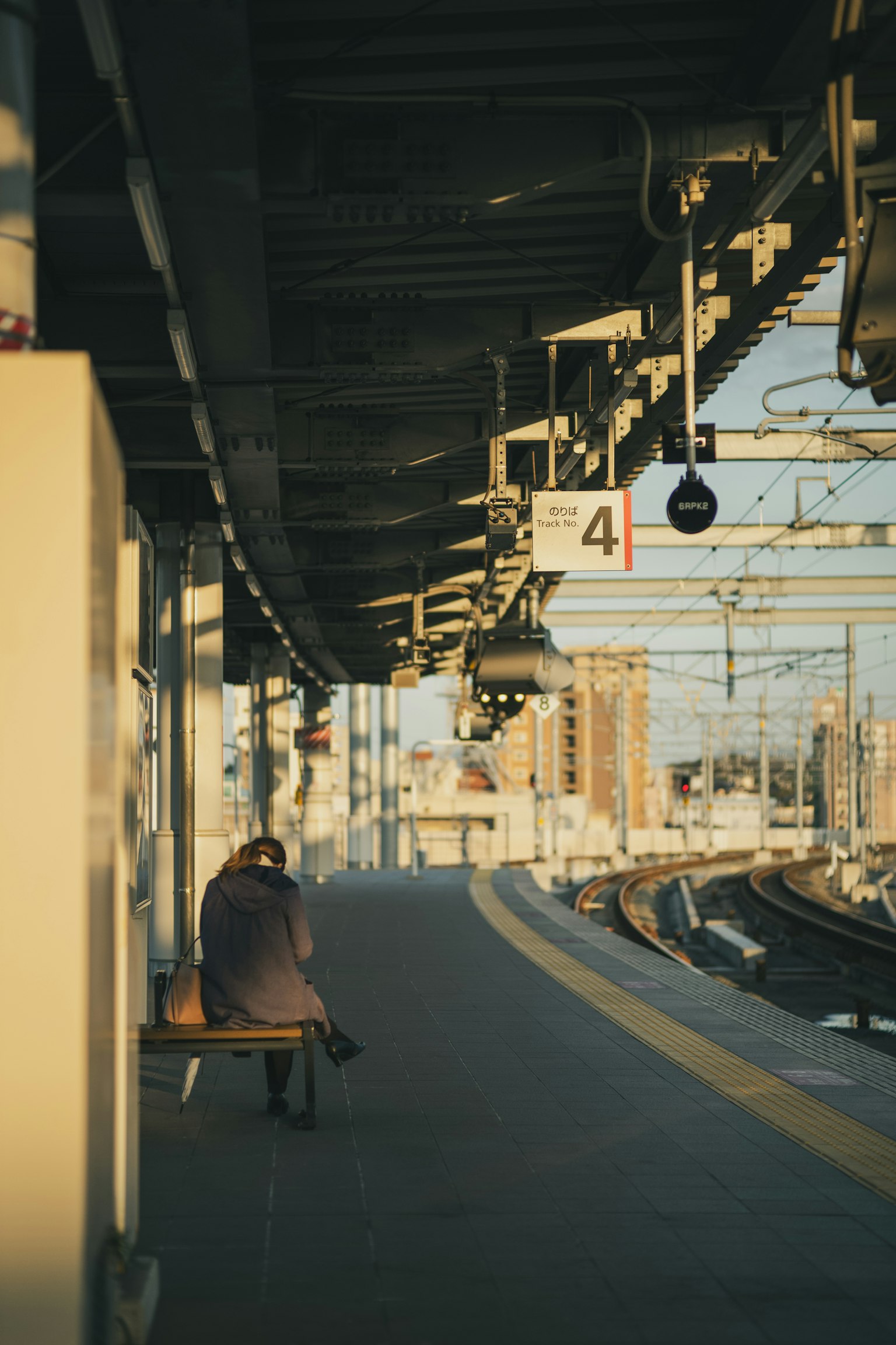 Person sitzt auf einem Bahnsteig in der Dämmerung