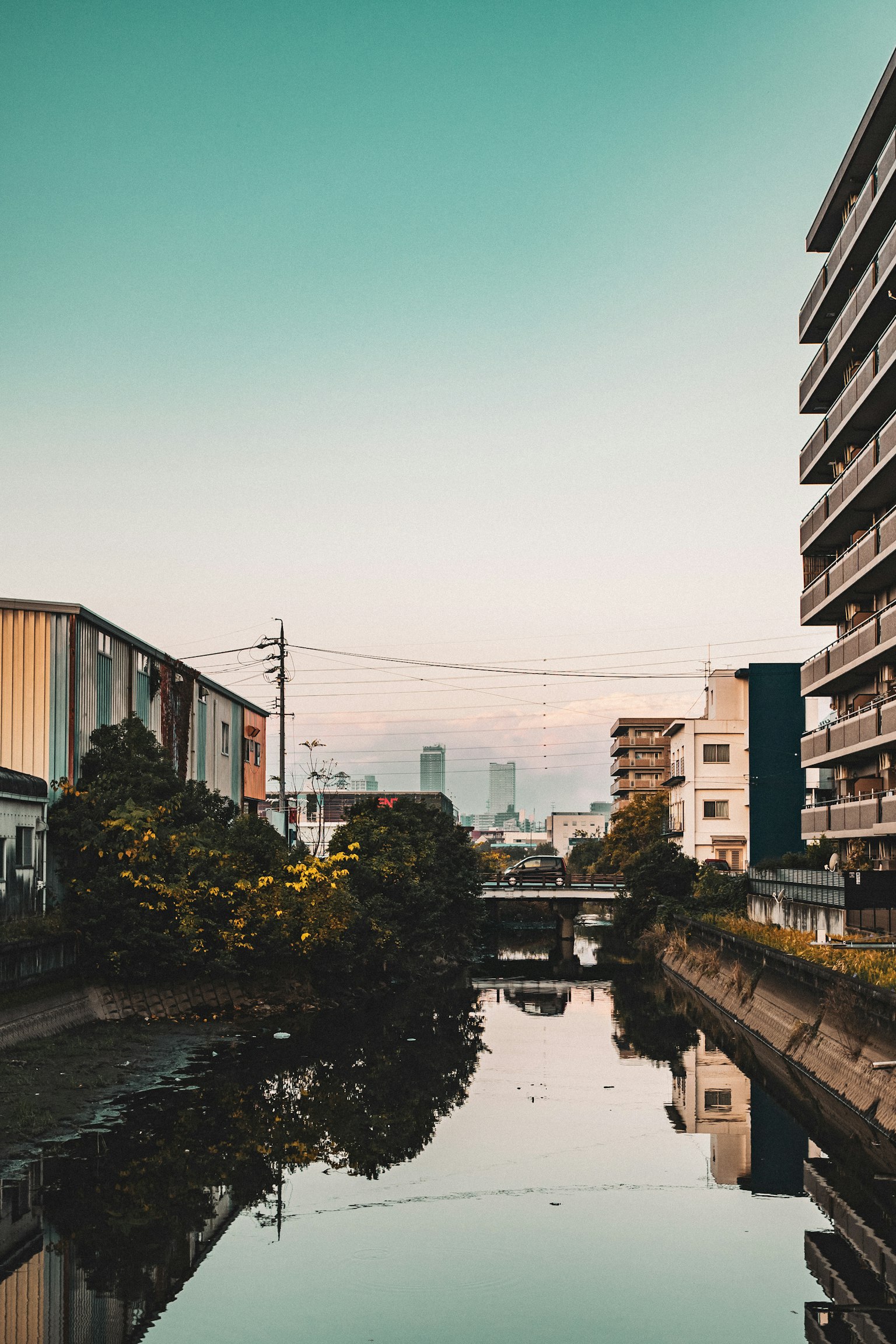 Paisaje urbano con un río tranquilo y edificios cercanos bajo un cielo azul