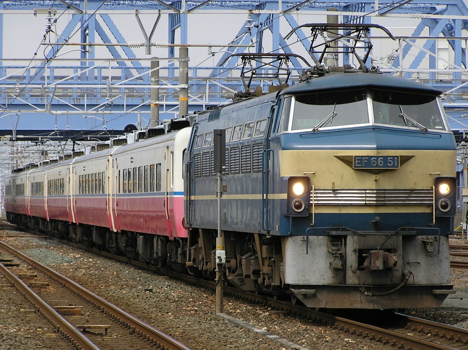 Kereta yang berhenti di bawah jembatan kereta api biru