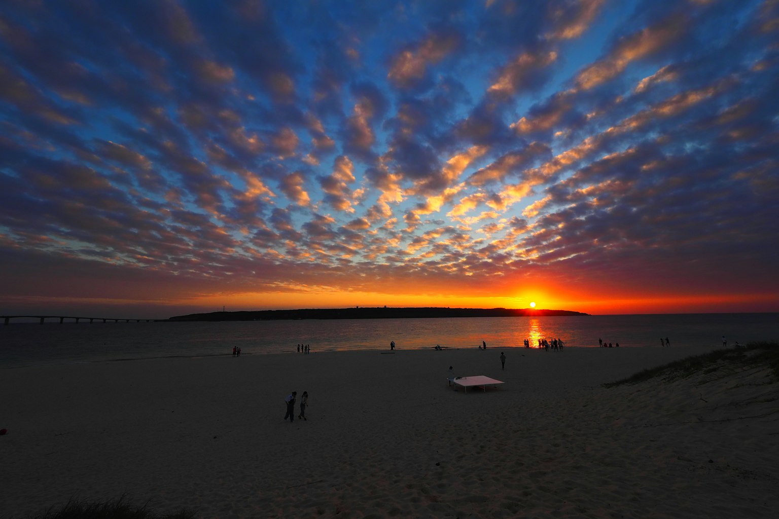 Splendido tramonto sulla spiaggia con nuvole vivaci e silhouette di persone
