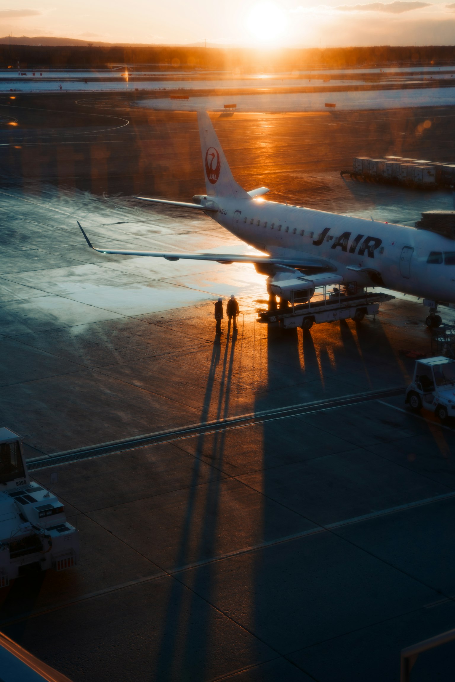 Airplane on airport runway with sunset in background and long shadows