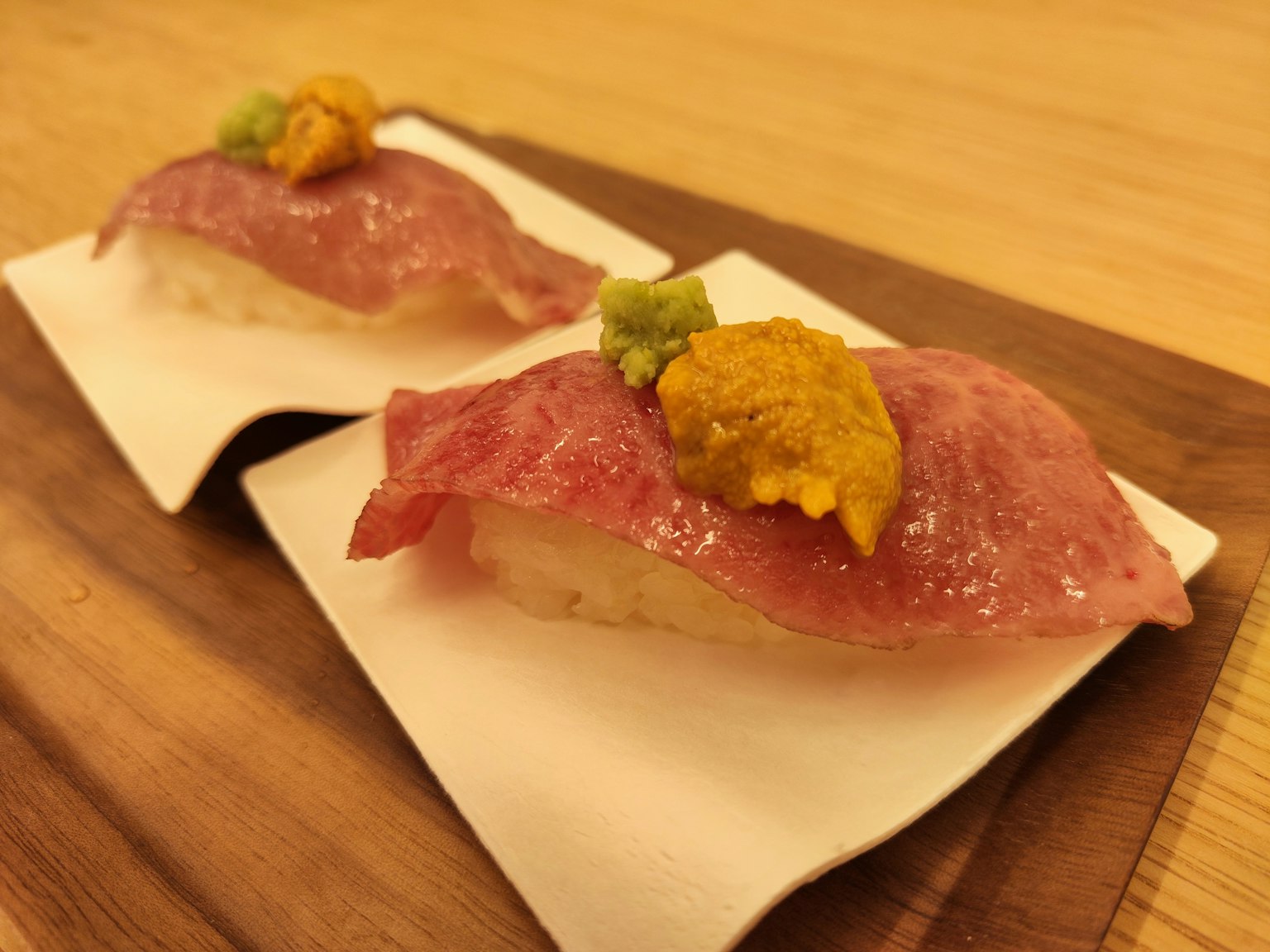 Sushi delicioso con rodajas de pescado cubiertas con uni y wasabi en un plato de madera