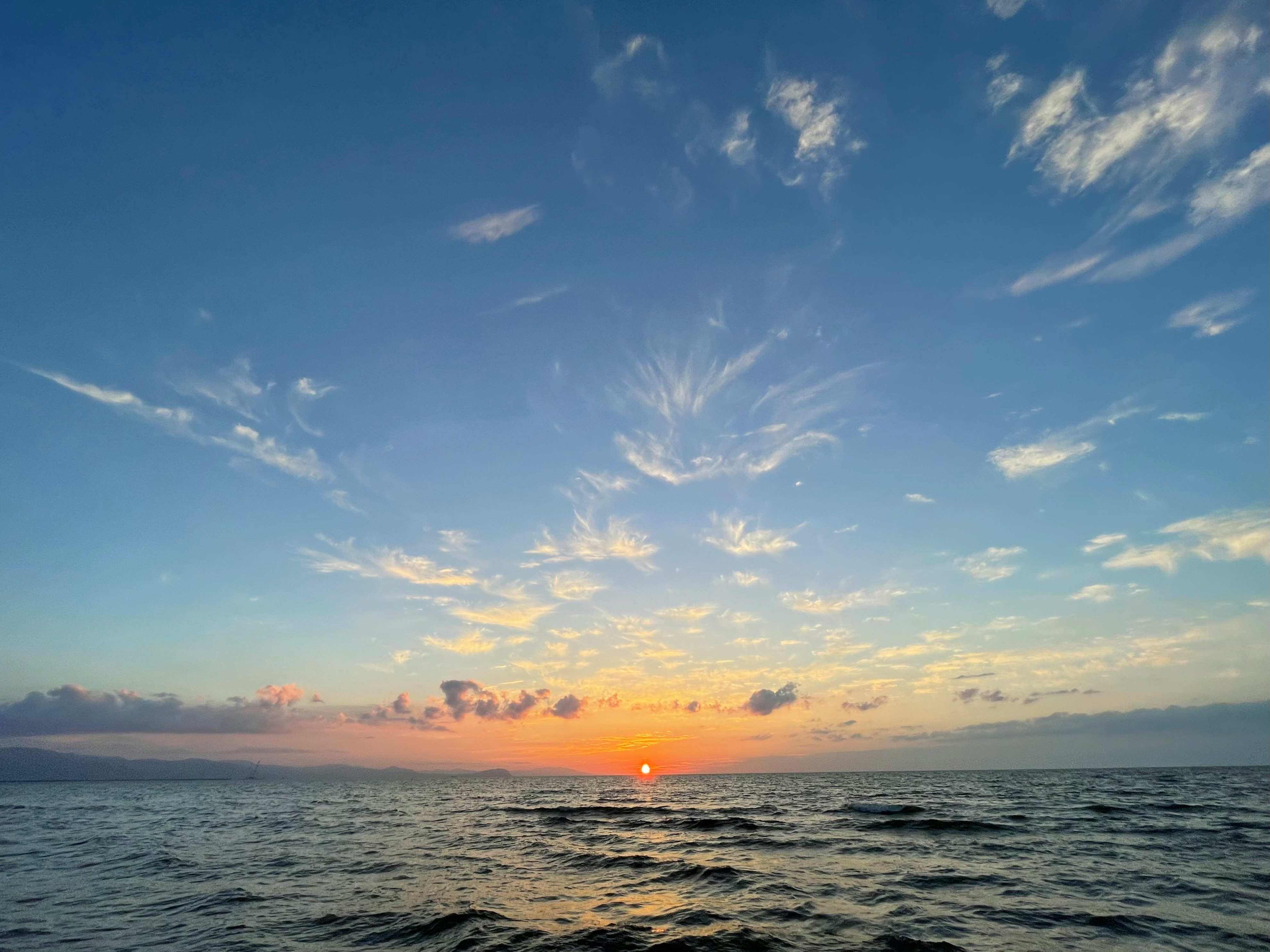 水平線に沈む夏の夕日と穏やかな海