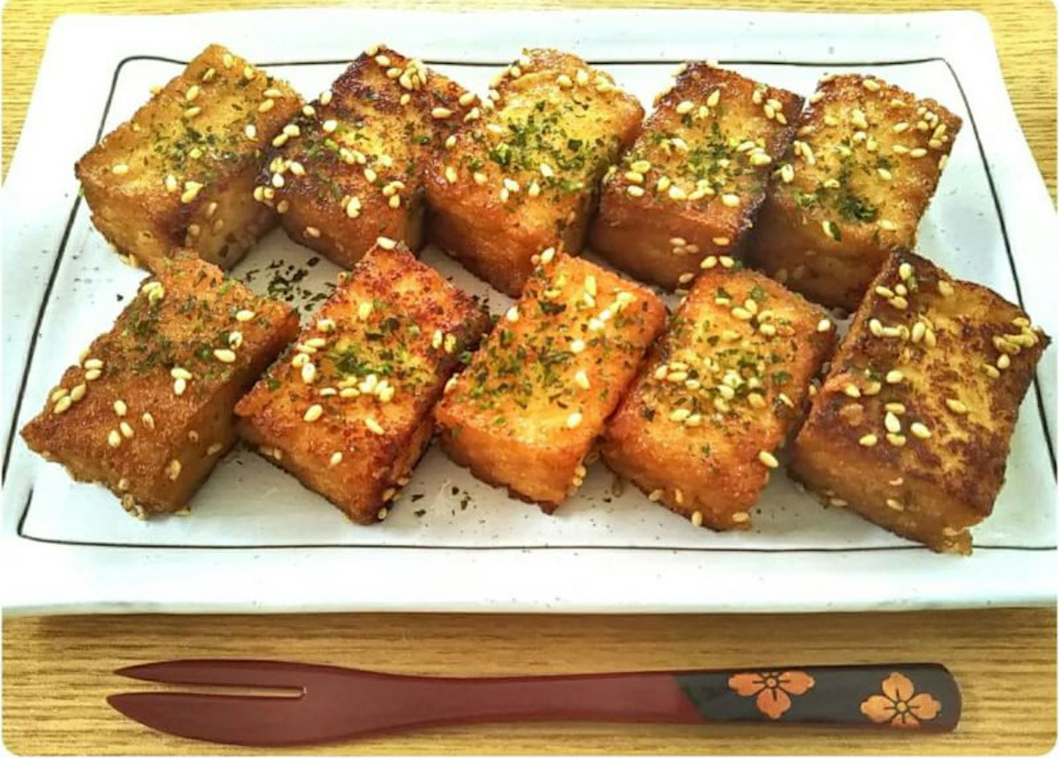 Platte mit goldenen frittierten Tofu-Blocken, garniert mit Sesamsamen