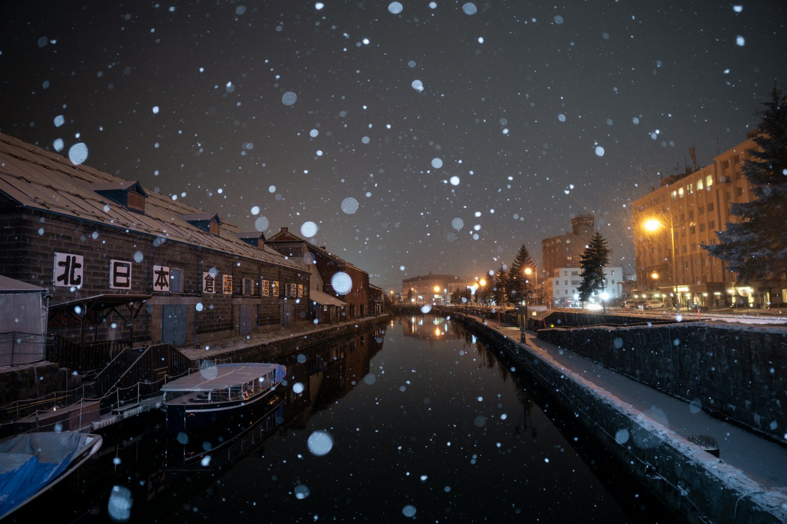 Neve che cade su un canale con edifici illuminati di notte
