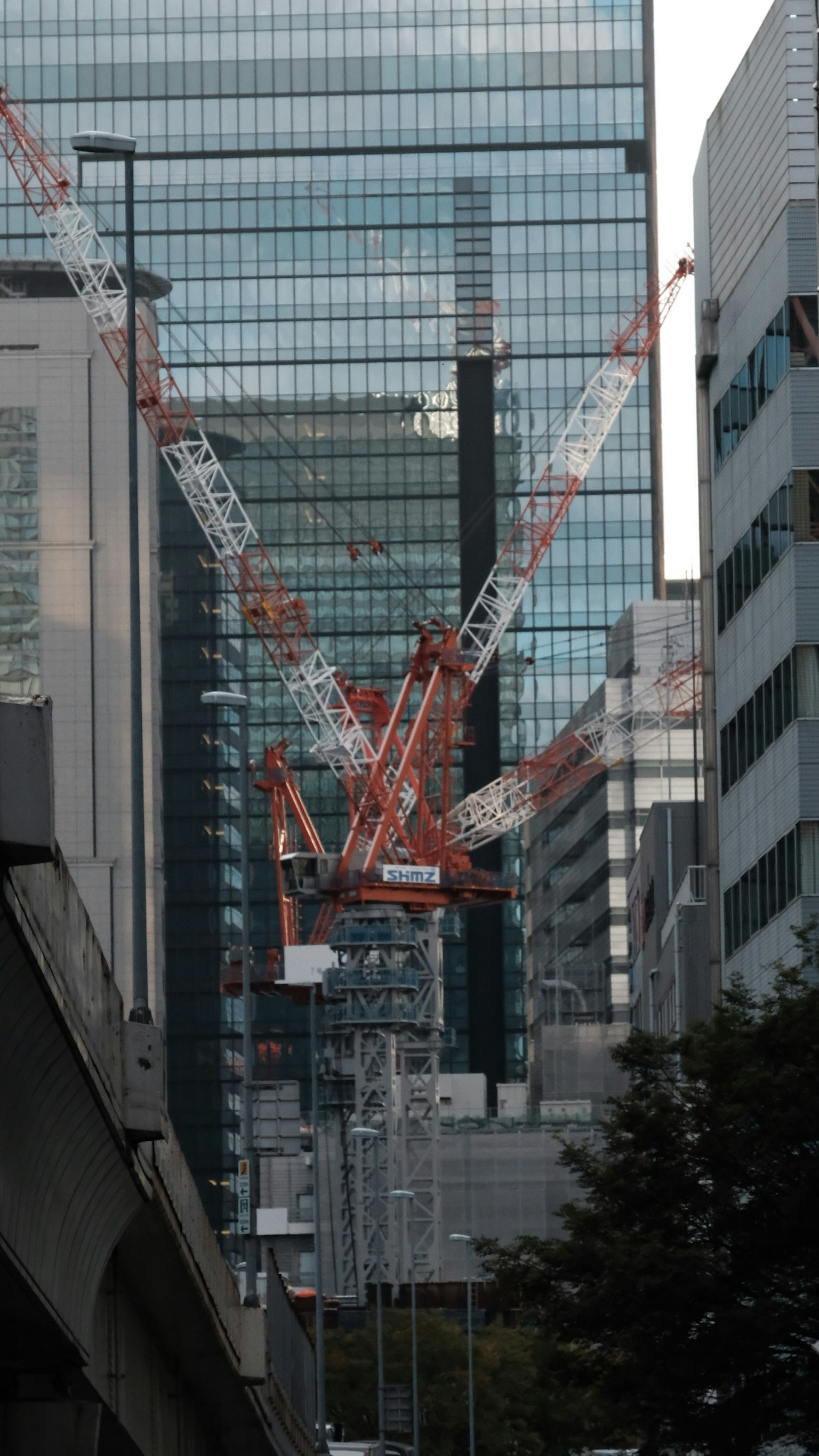 高層ビルの間にあるクレーンとガラスのファサード