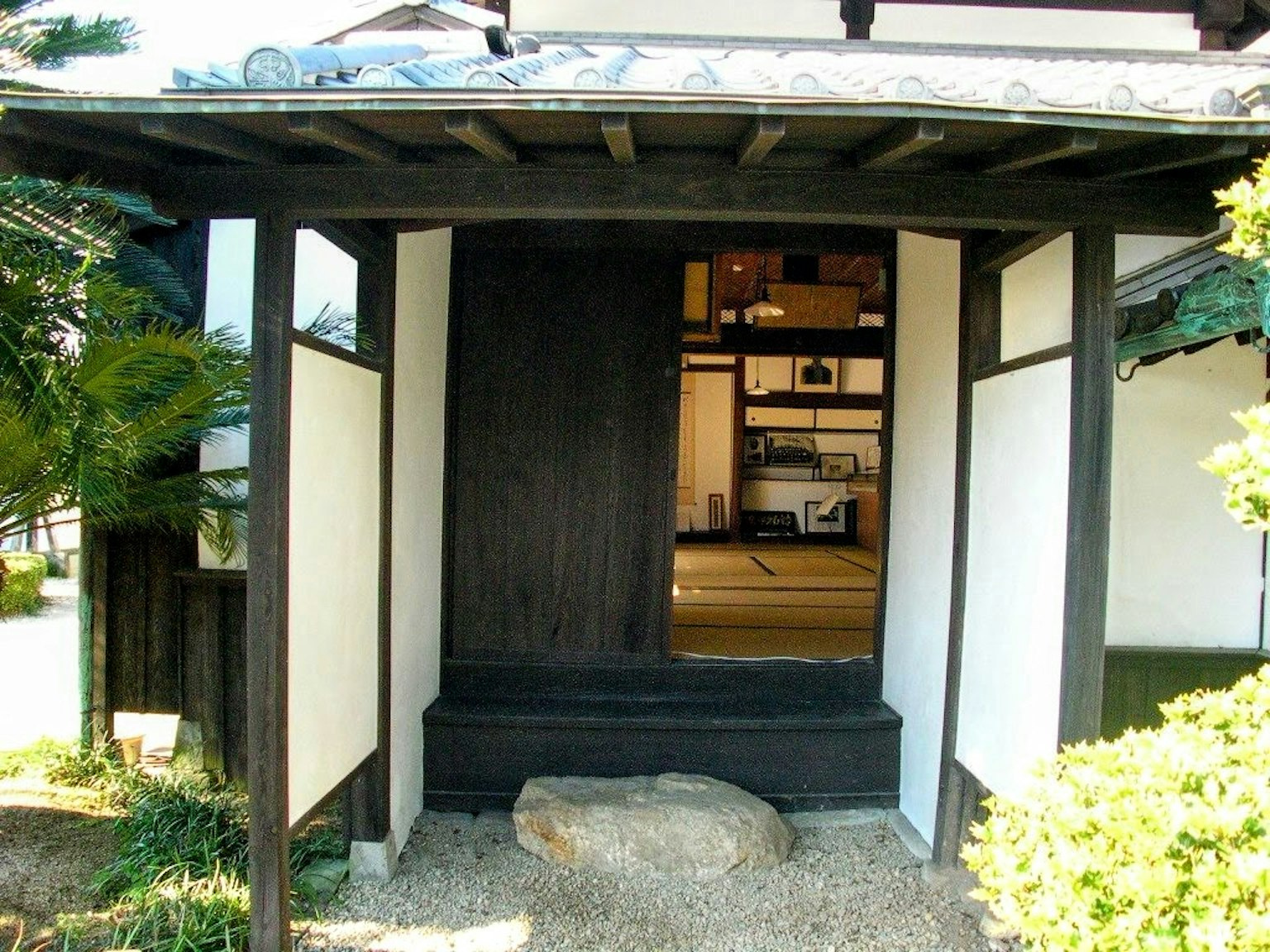 Entrée d'une maison japonaise traditionnelle avec des murs blancs et du bois foncé