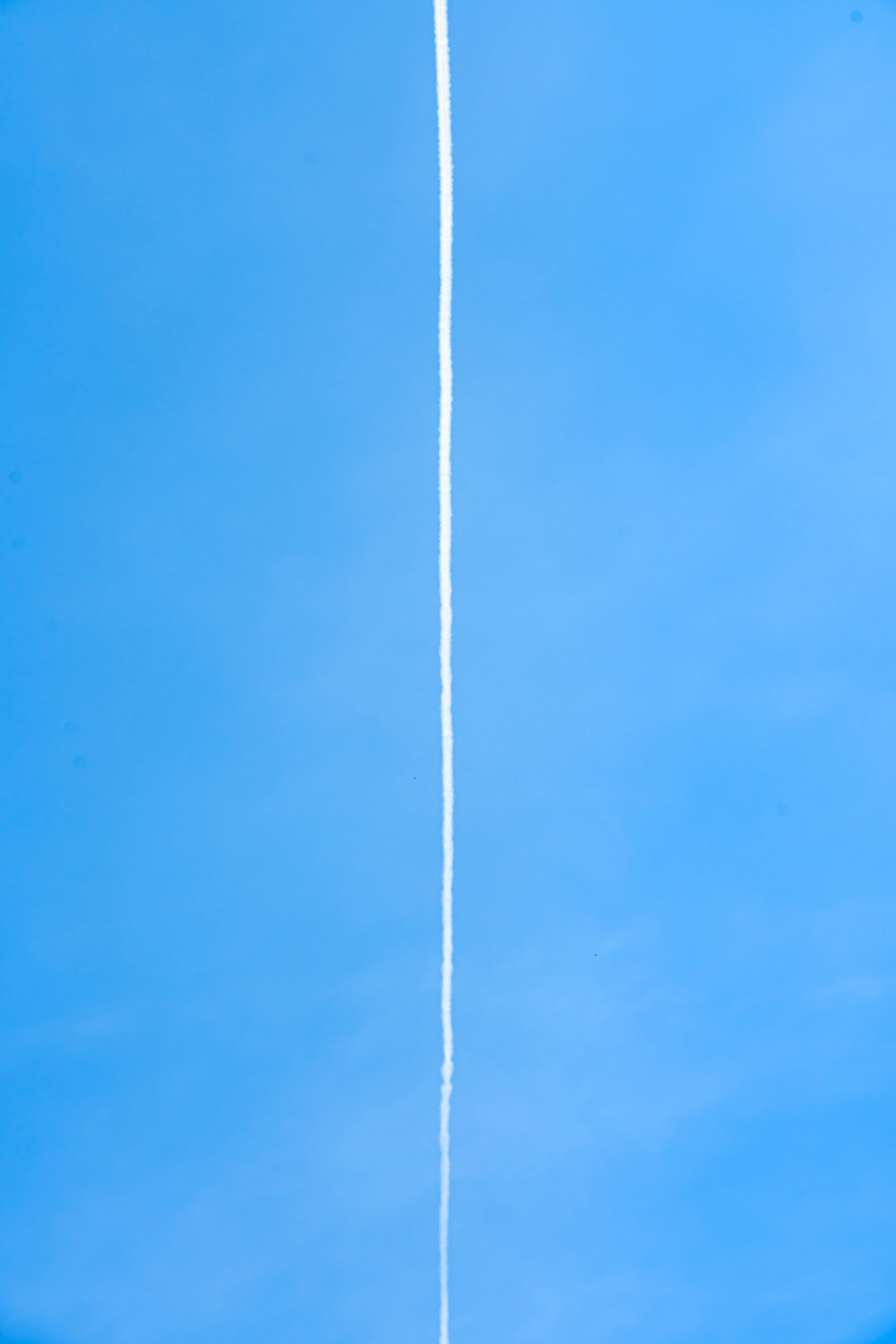 青空に伸びる白い線のような光