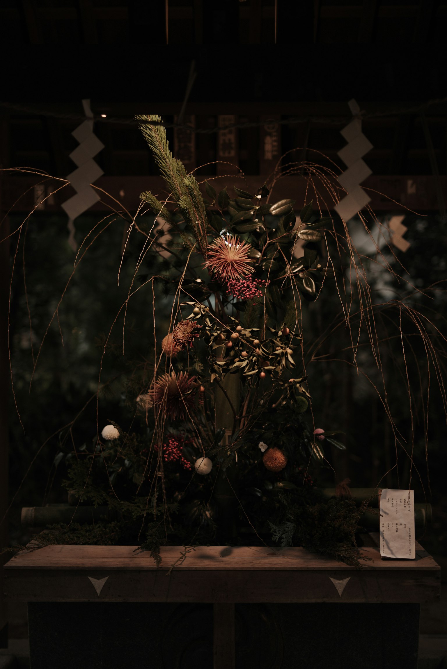 Ein Blumenarrangement mit lebhaften Blumen und Gräsern vor einem dunklen Hintergrund