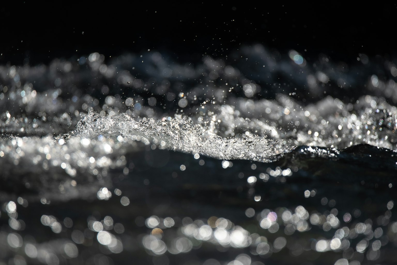 水の波紋と飛沫が輝く暗い背景の画像