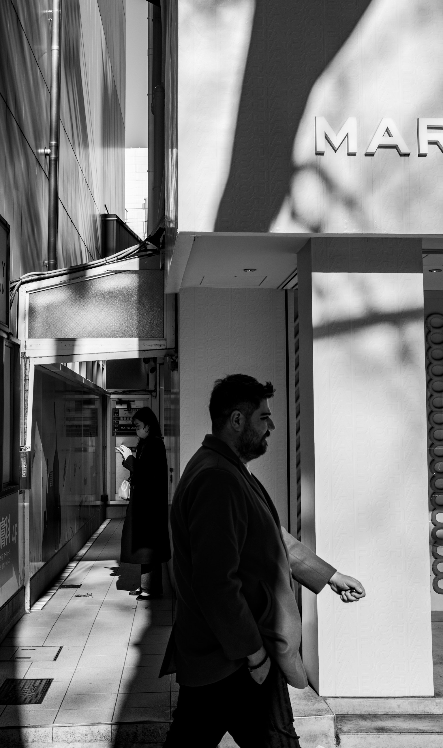 A man walking in a black and white city scene with a woman silhouette